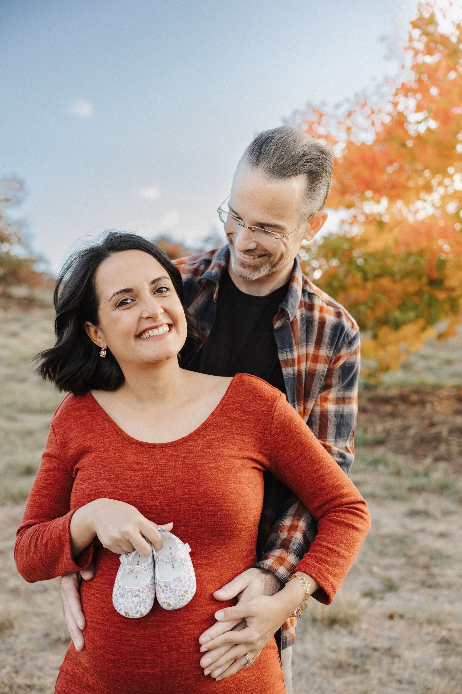 happy couple in Canberra maternity photoshoot with baby shoes
