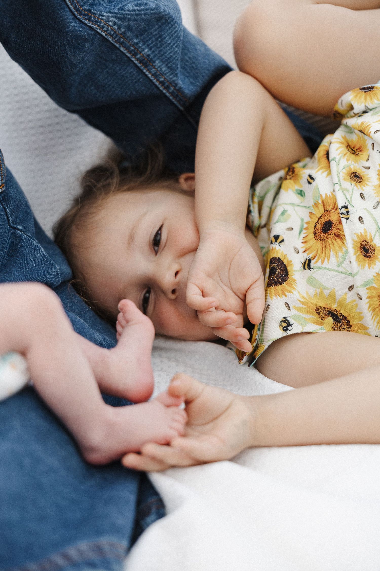 A sister tickles her baby brother's feet in newborn photoshoot in Canberra