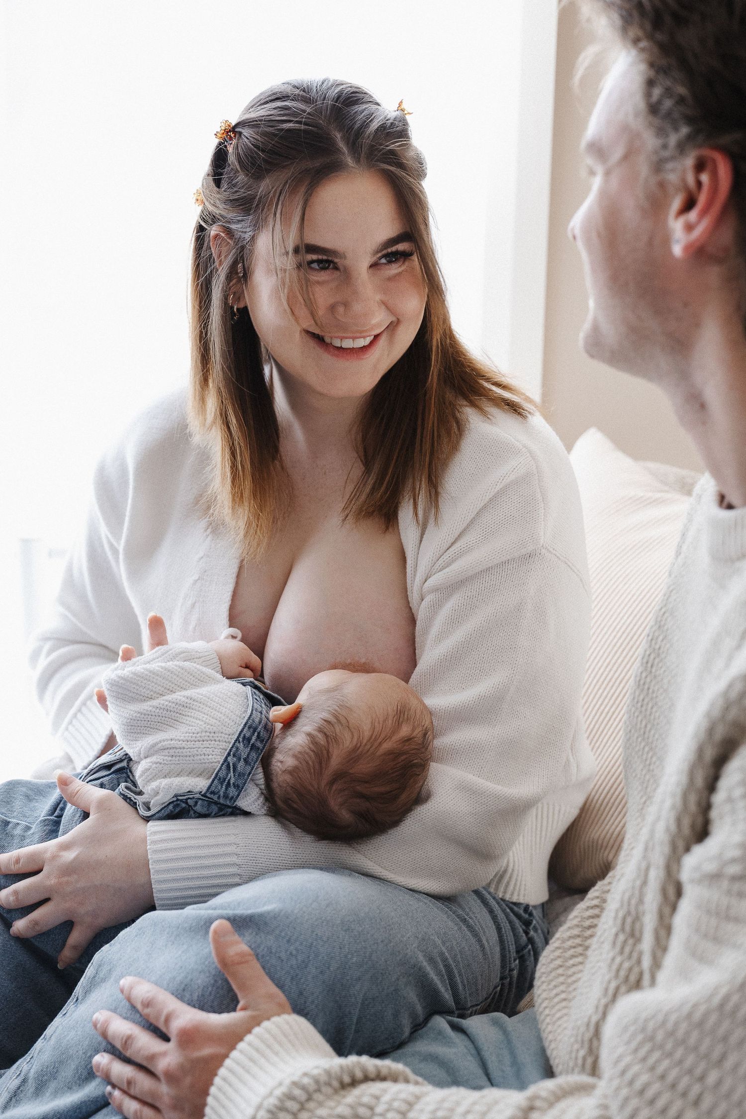 Smiling couple with breastfeeding baby in newborn baby photoshoot in Canberra