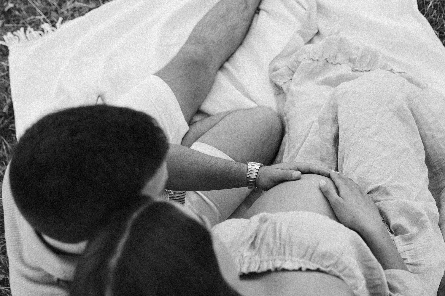 Black and white picture of couple with hands on a pregnant belly during an outdoor maternity photoshoot in Canberra