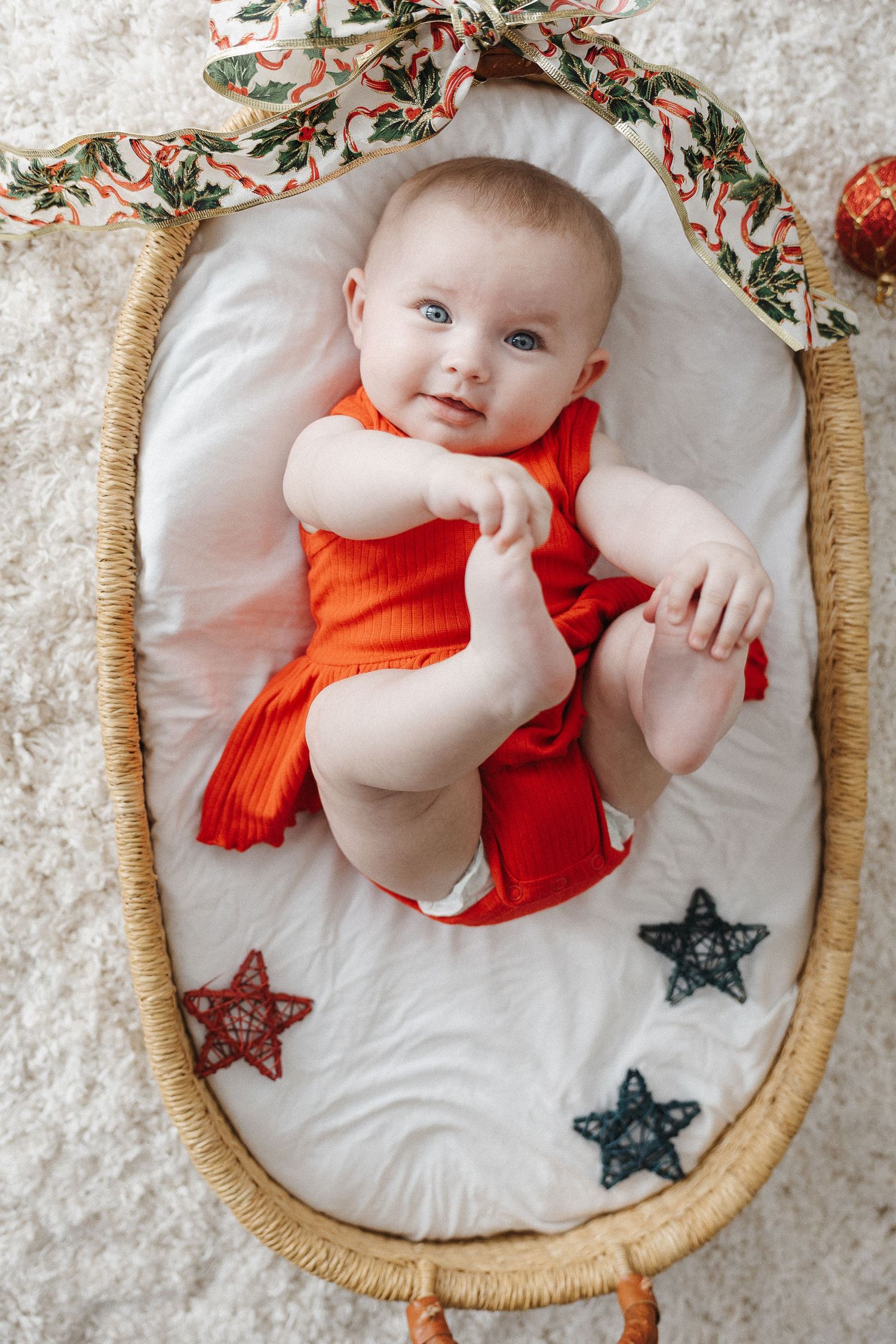 Beautiful baby girl grabs her feet in a Christmas mini photo session in Canberra