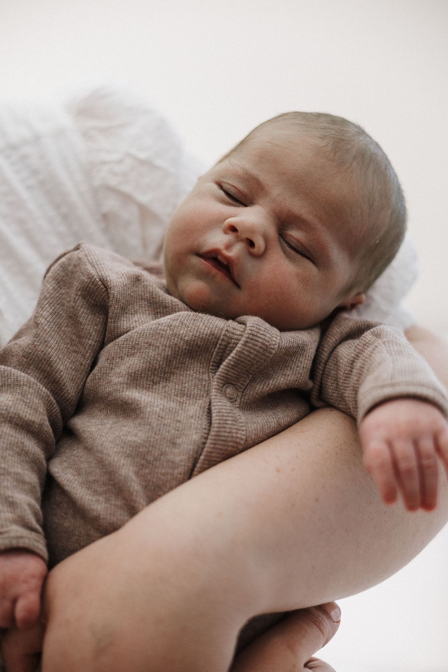 Baby sleeps in his mums arms in Canberra photography studio