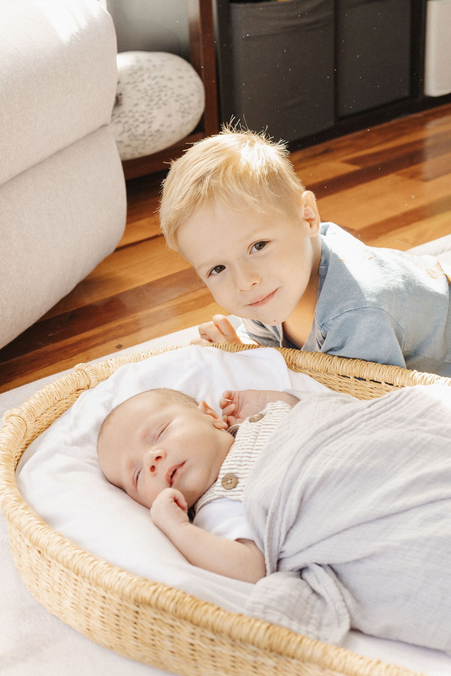Proud big brother lies next to his sleeping newborn baby brother in Canberra