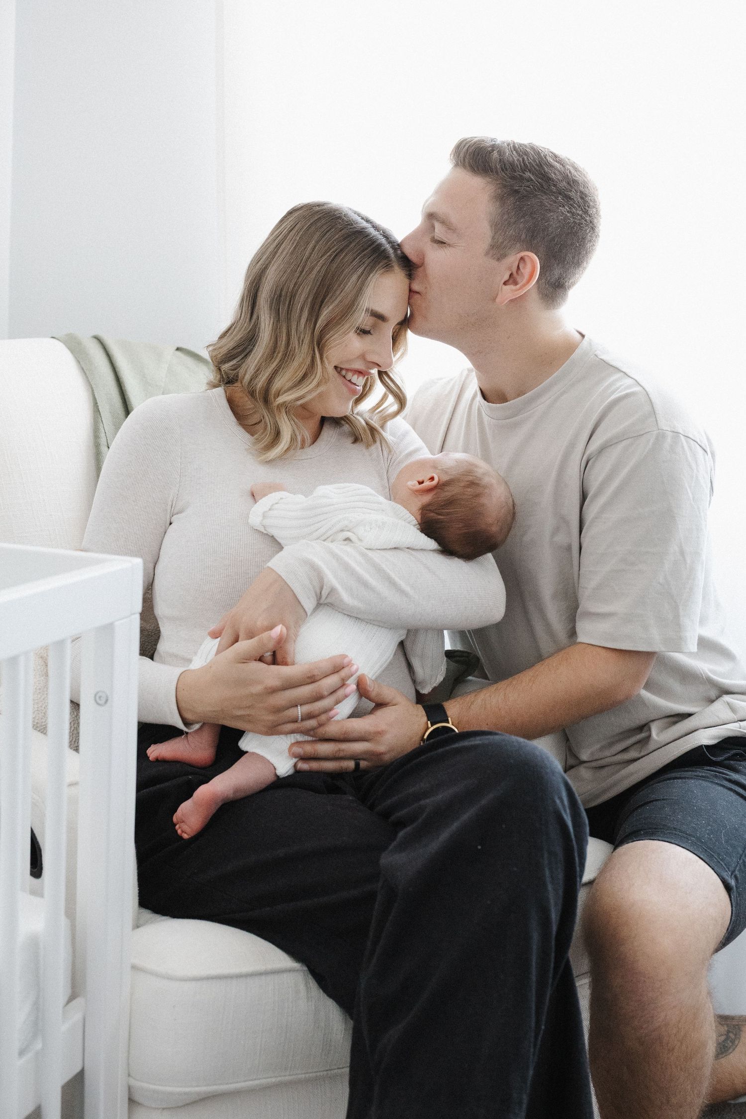 Father kisses mother with newborn baby in Canberra
