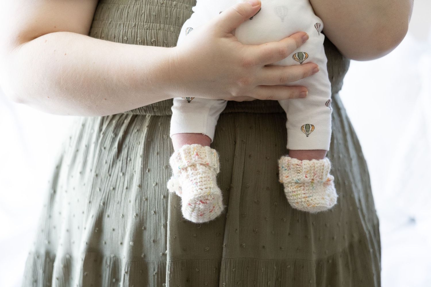 newborn baby's feet and legs cuddled by mum in photography studio canberra