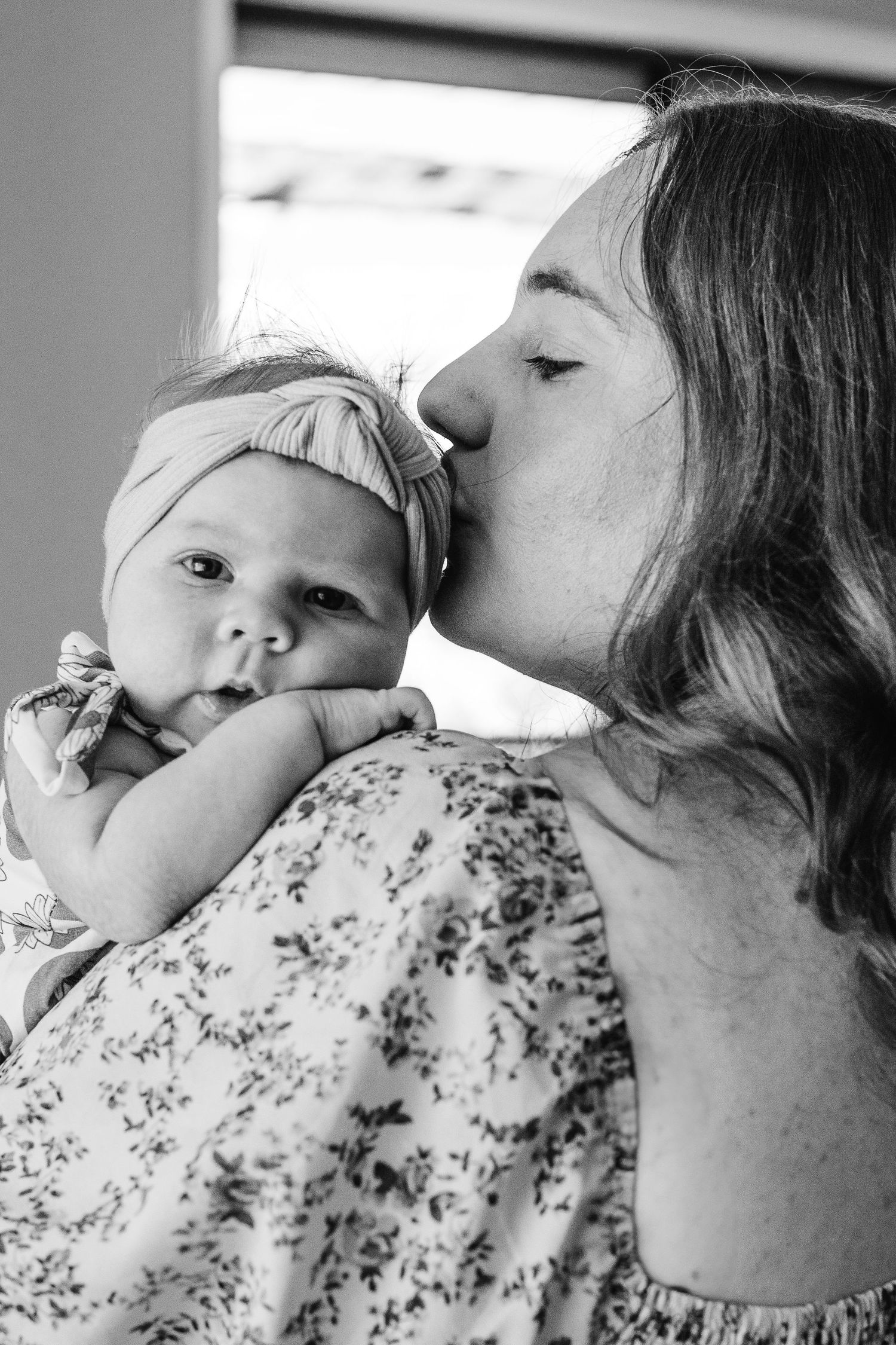 Black and white photograph of mother kissing her newborn baby in Canberra