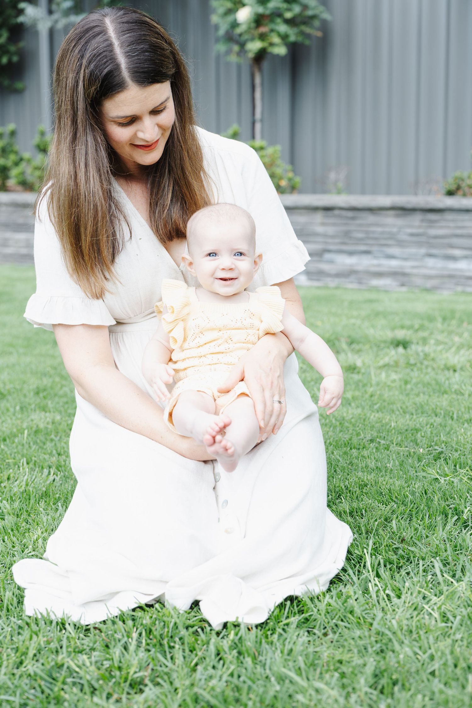 Canberra family photoshoot with mum cuddling baby on the back lawn