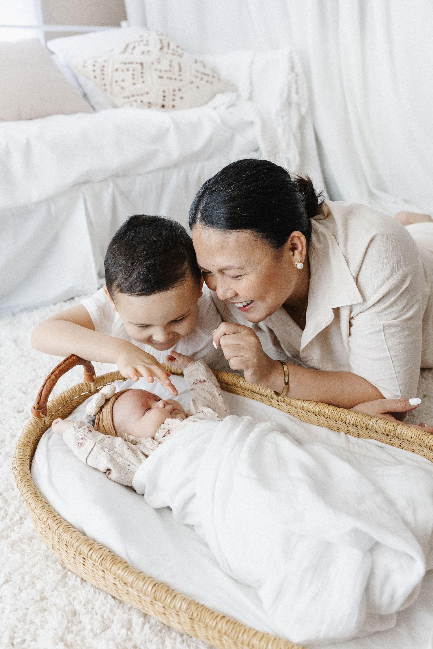 Mum and big brother look at baby in a basket in Canberra newborn studio photoshoot