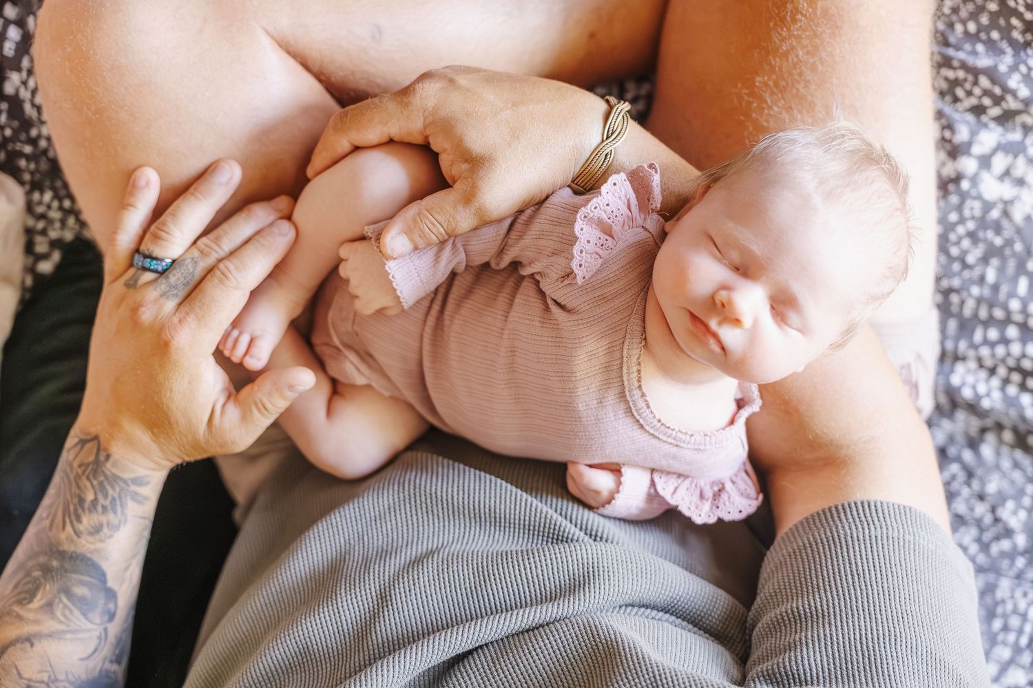 Dad holds baby in his lap in newborn photoshoot Canberra