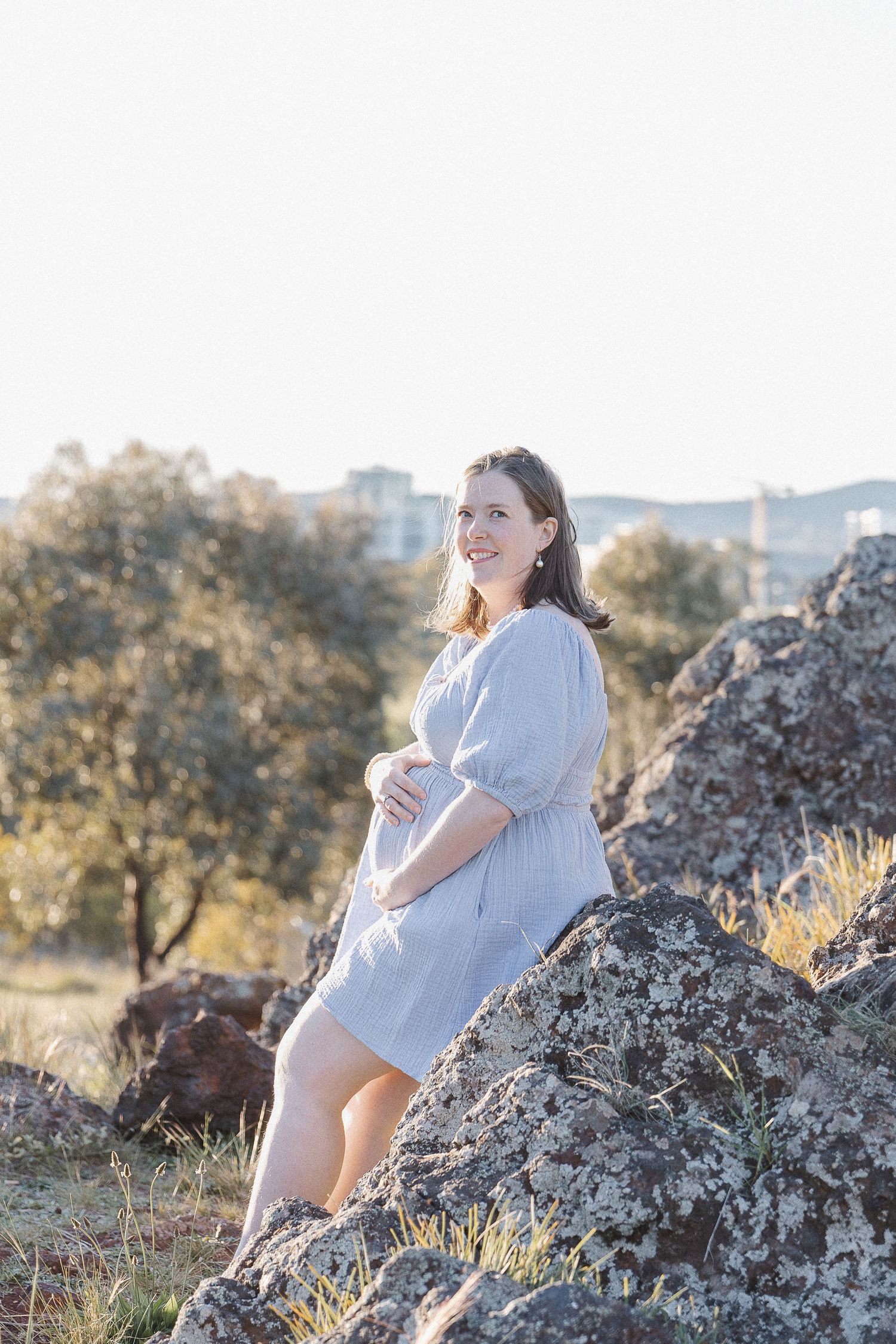 Pregnant woman rests on a rock in Canberra maternity photoshoot