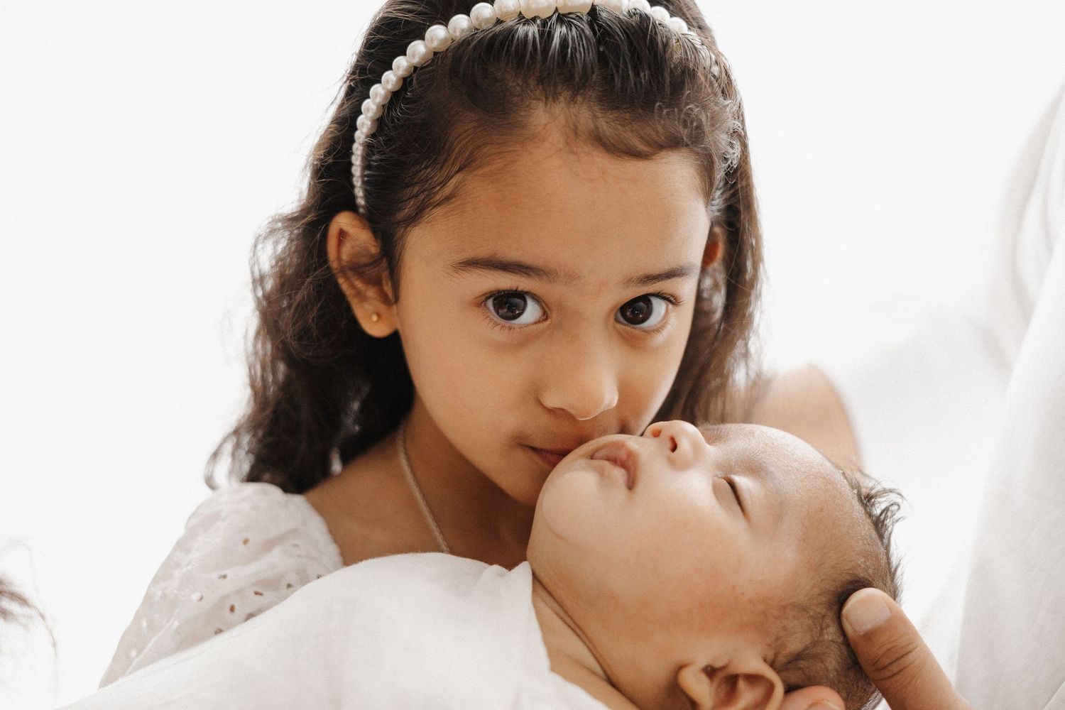 Proud big sister kisses her newborn baby brother in Canberra
