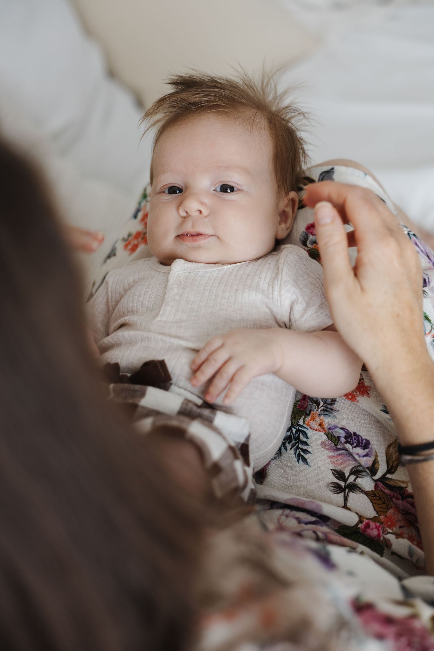 Baby peeks out from his mums lap during newborn photoshoot in Canberra
