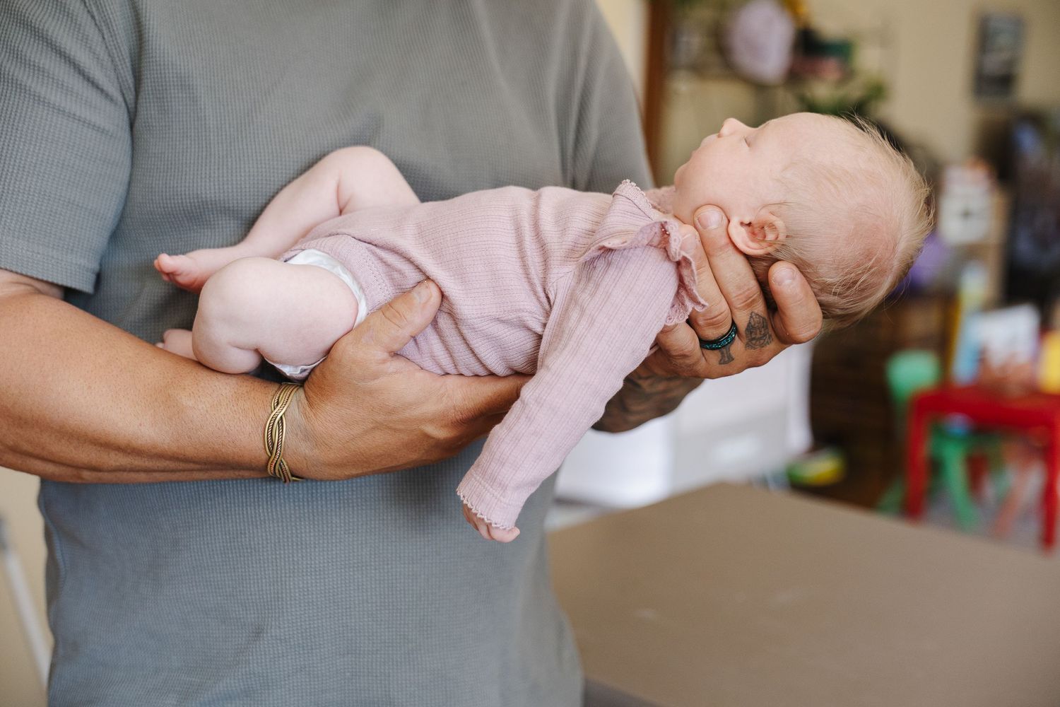 A newborn baby girl is held by her father in a Canberra newborn photoshoot