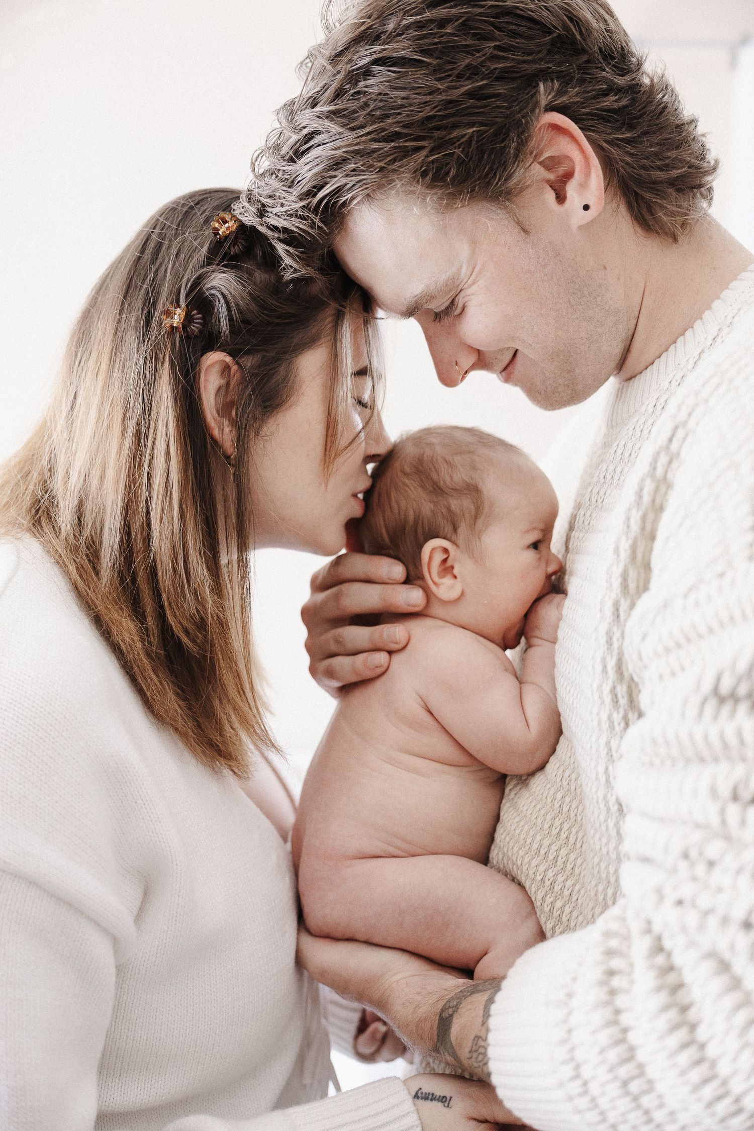 Two doting parents look at their naked newborn baby in Belconnen Canberra photography studio