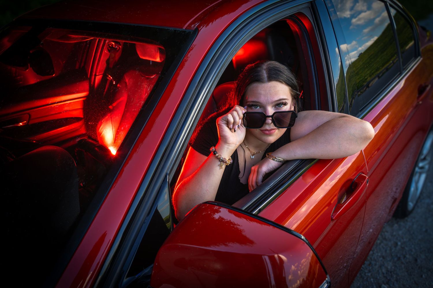 Cali poses for a photo in the front seat of her new BMW car during her senior portrait photo session in Des Moines, Iowa.