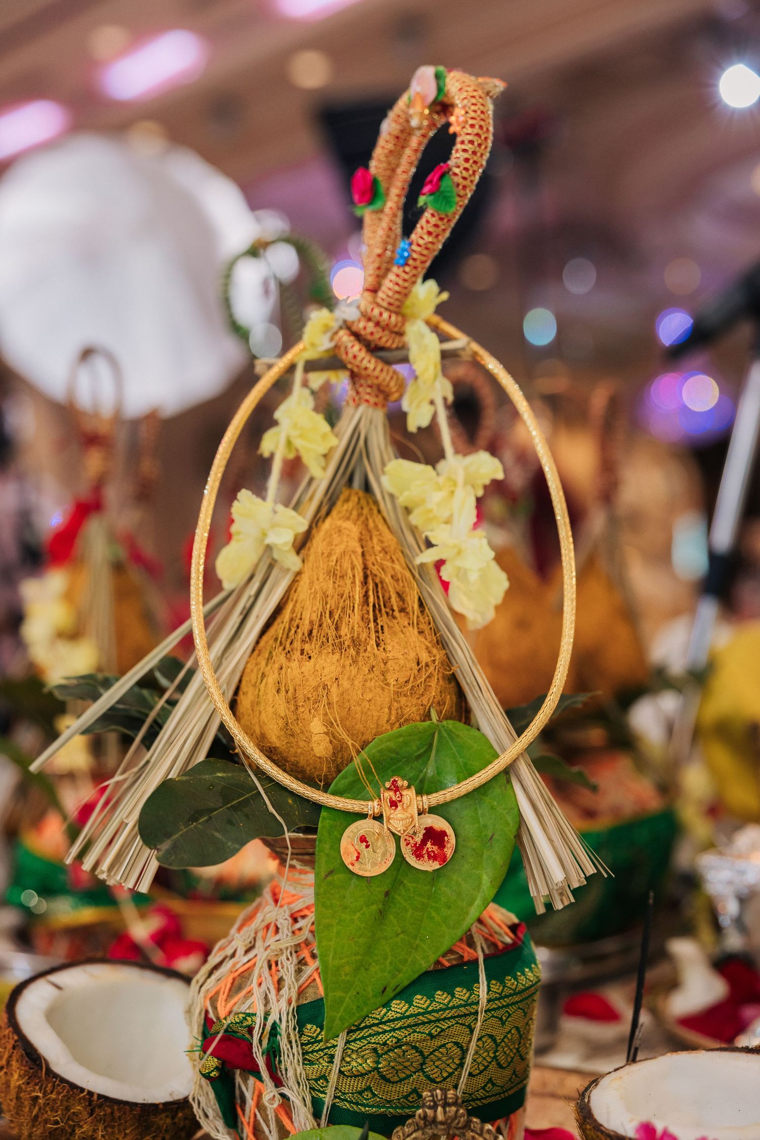 Traditional Thai wedding coconut decoration with floral ornaments, green leaves, and golden accessories at a ceremonial event.