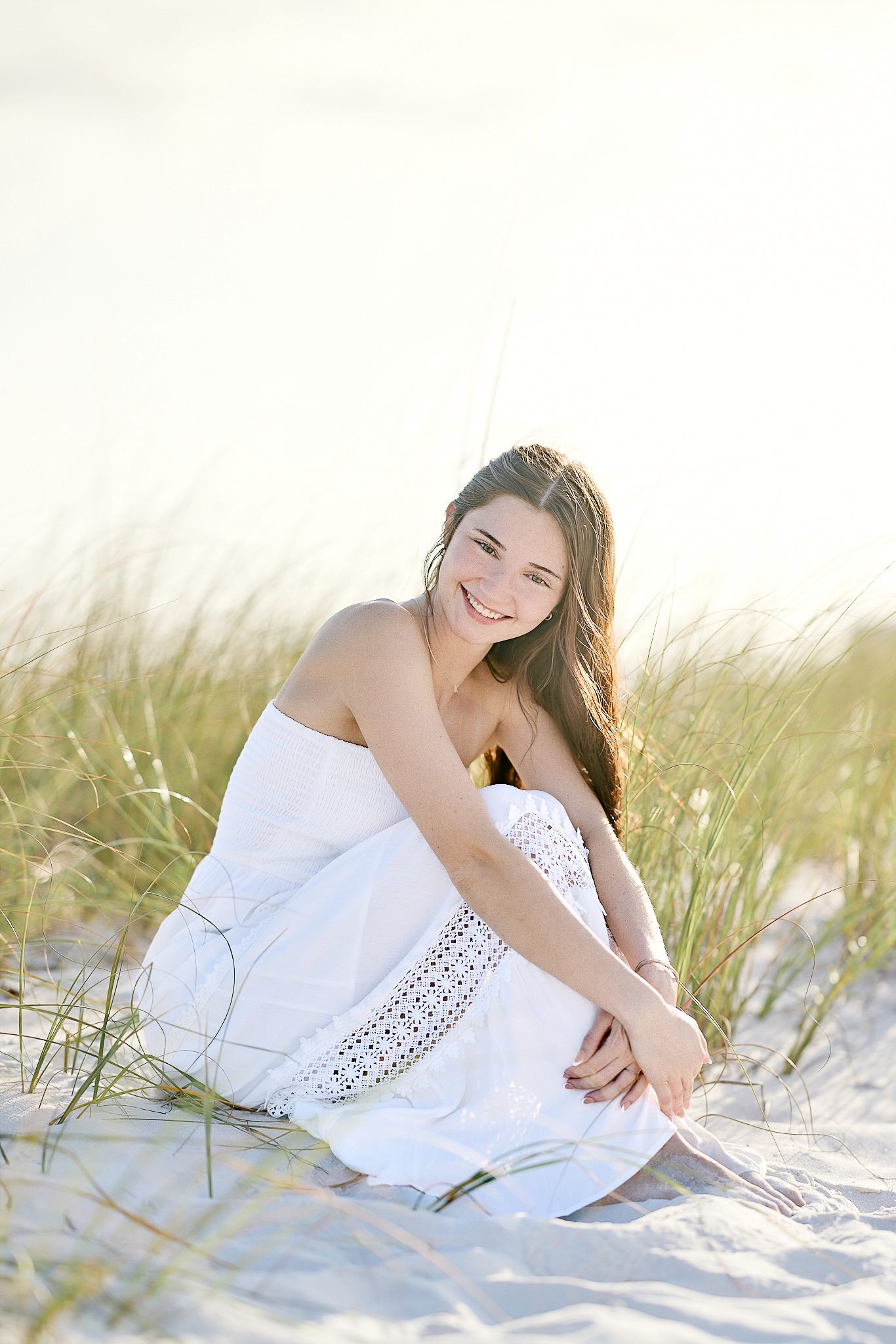 Sun-kissed beach portrait with flowing white dress in natural setting.