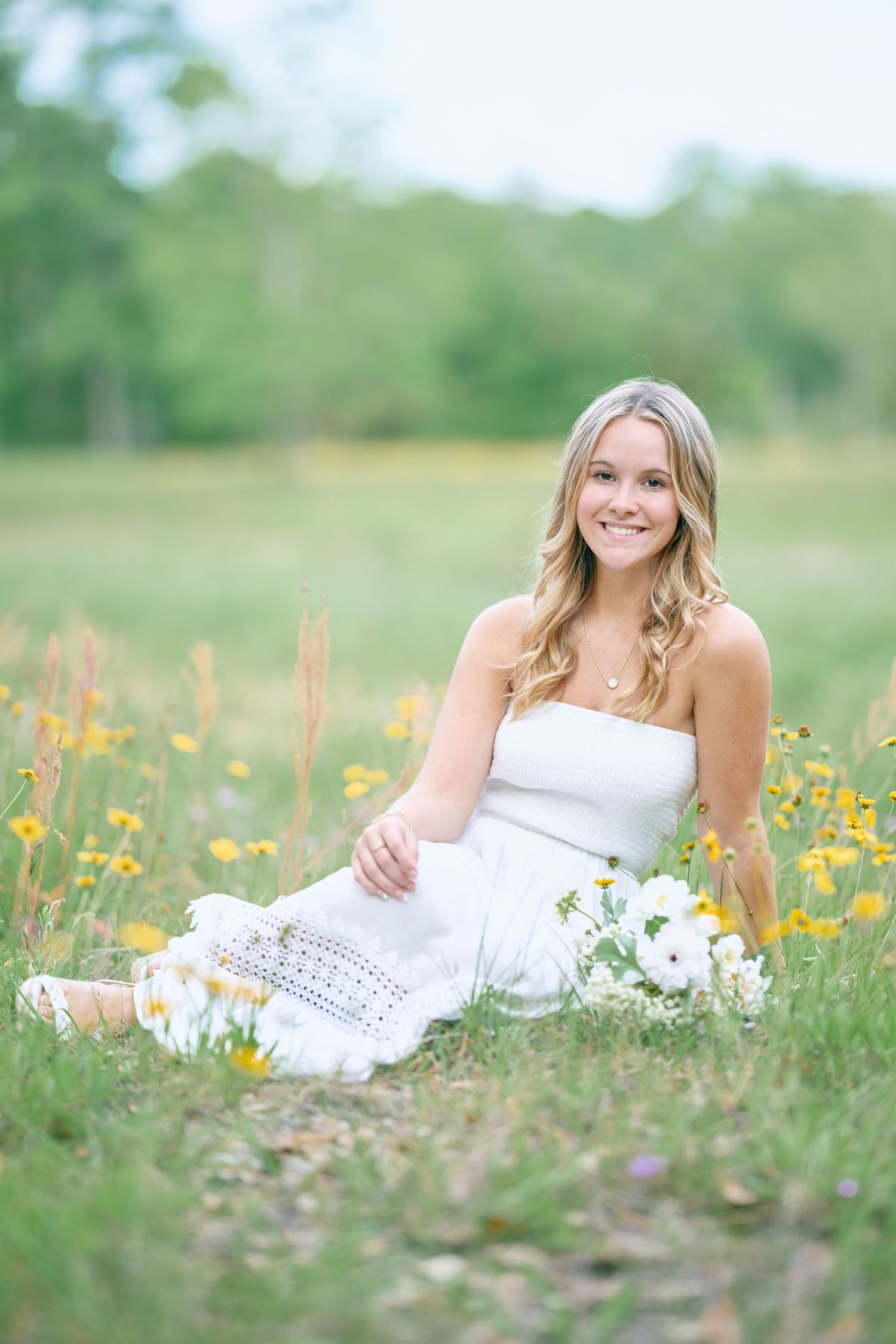 Dreamy outdoor photo in white dress surrounded by yellow wildflowers.