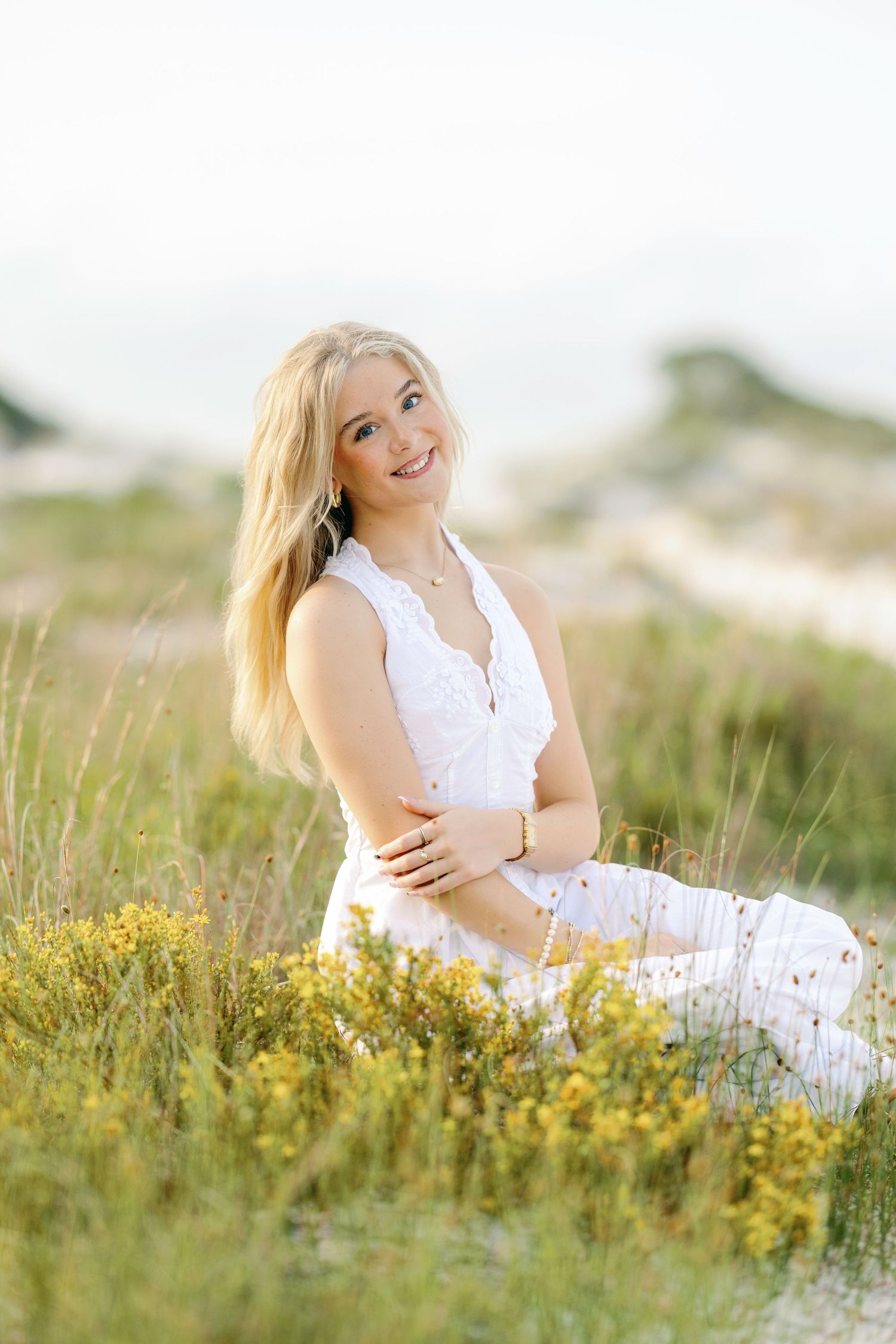 Person in white dress lying in a sunny meadow with wildflowers on a bright summer day.