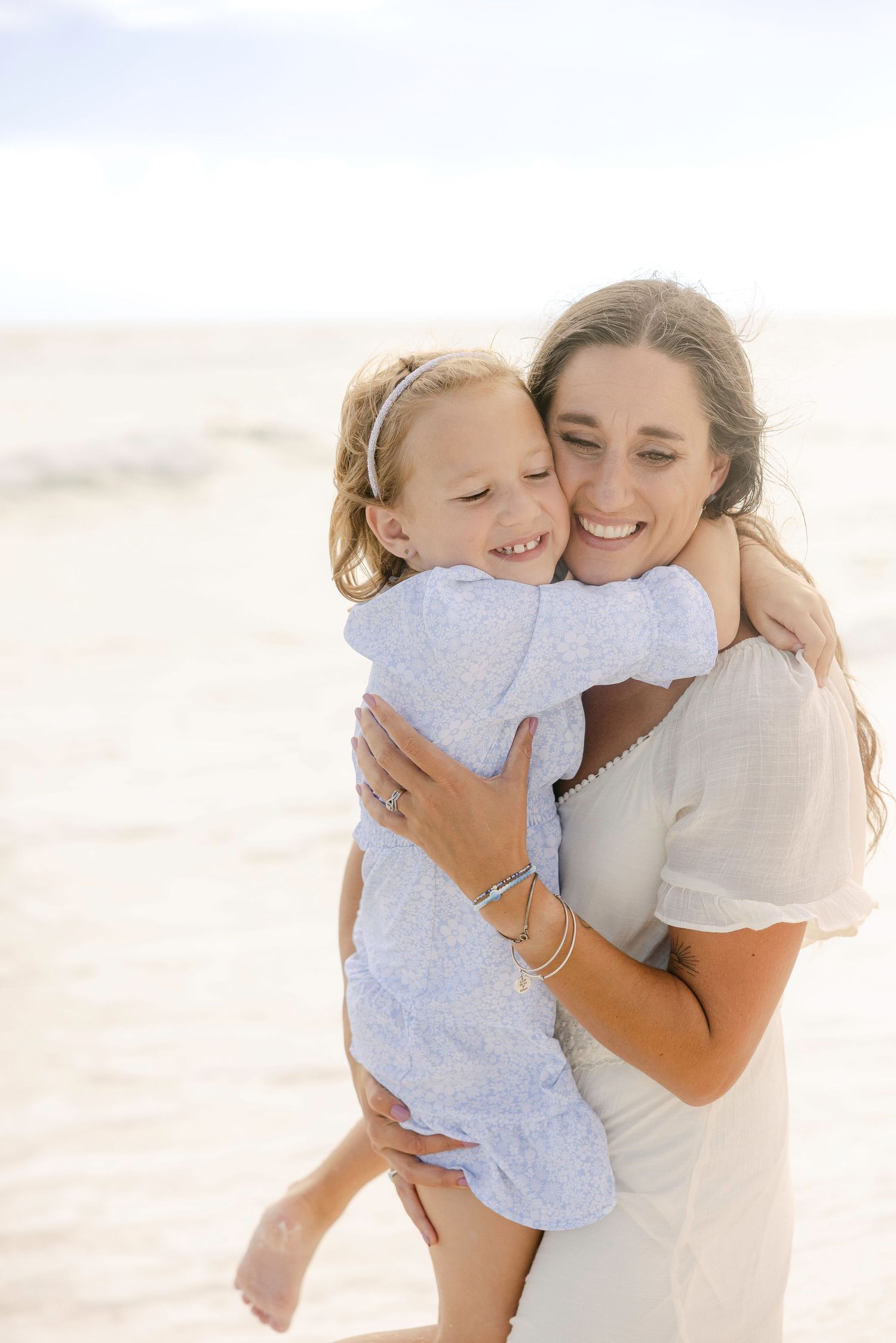 A tender embrace shared between parent and child on a bright, sunlit beach.