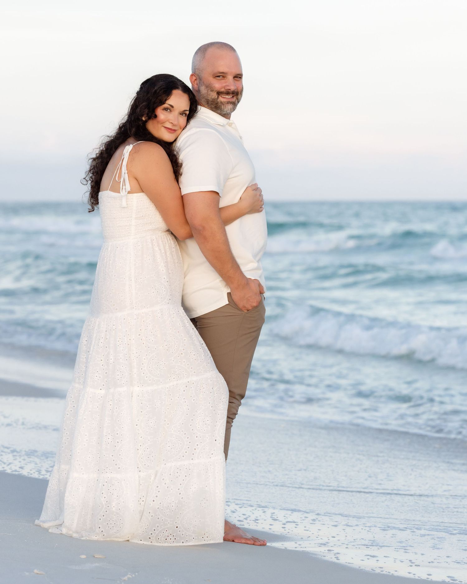 Couple embracing and smiling together on a beautiful ocean beach.