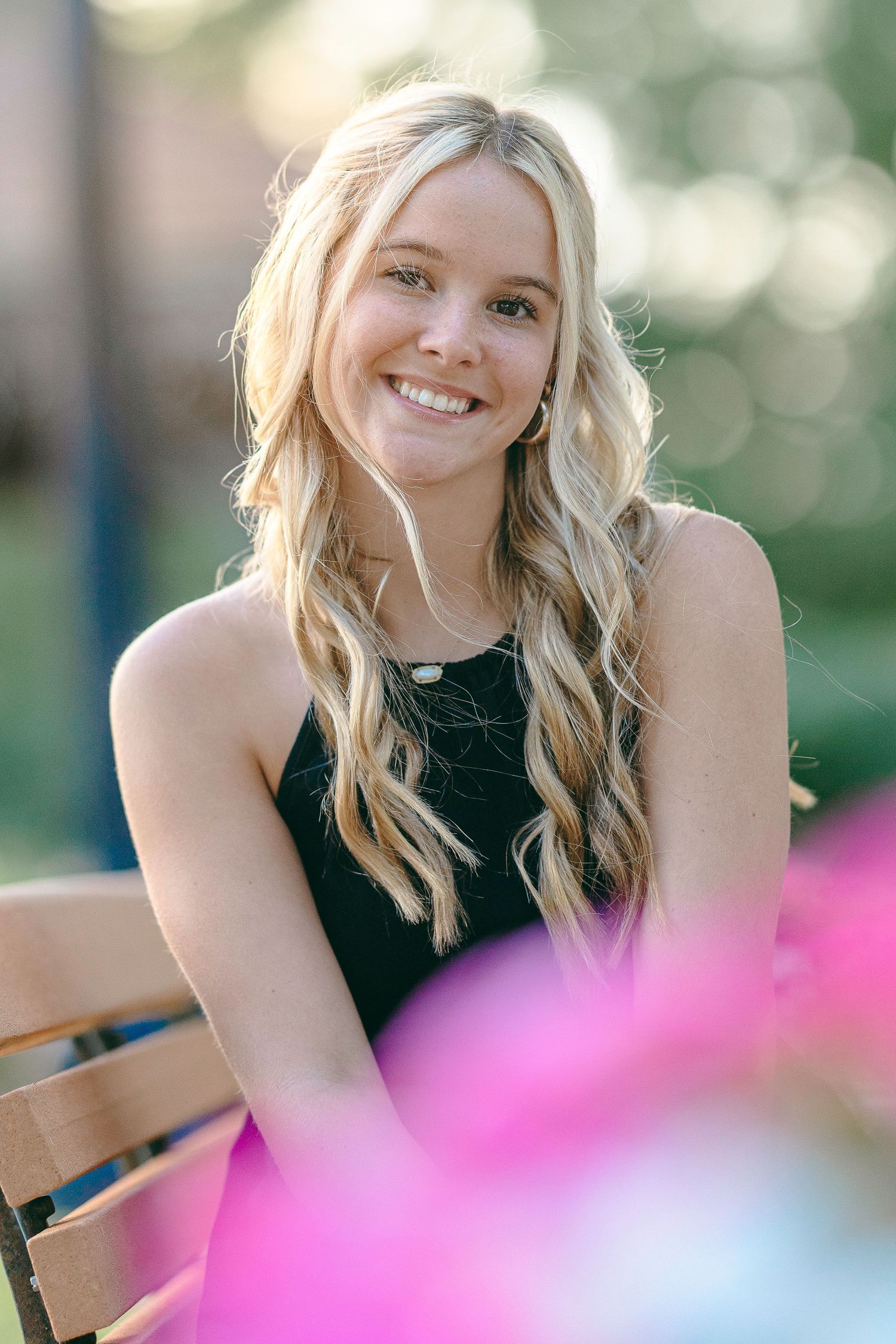 Soft bokeh background frames outdoor portrait series with pink floral accents.