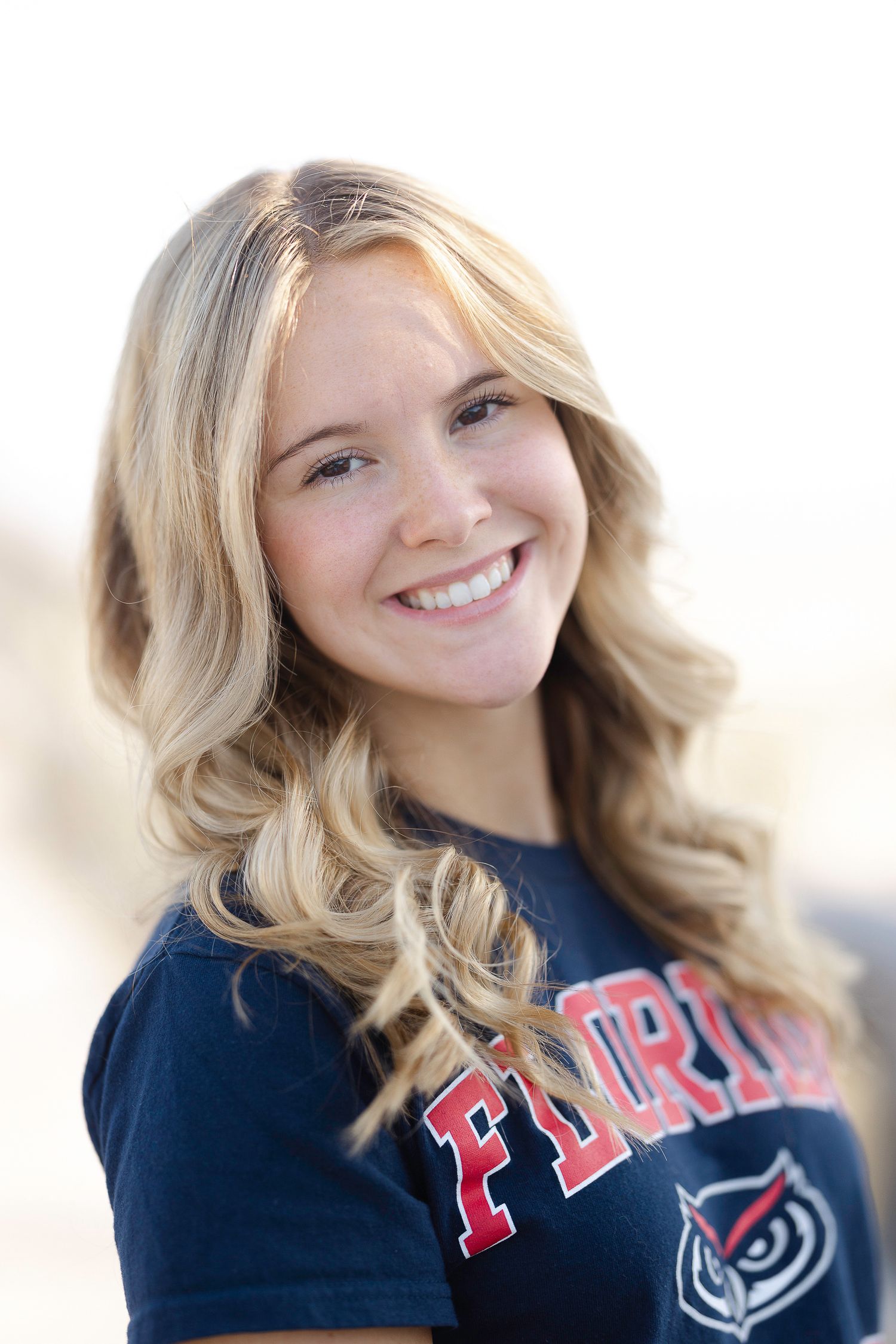 Person in Florida Atlantic athletic shirt smiles while posing against bright white background.