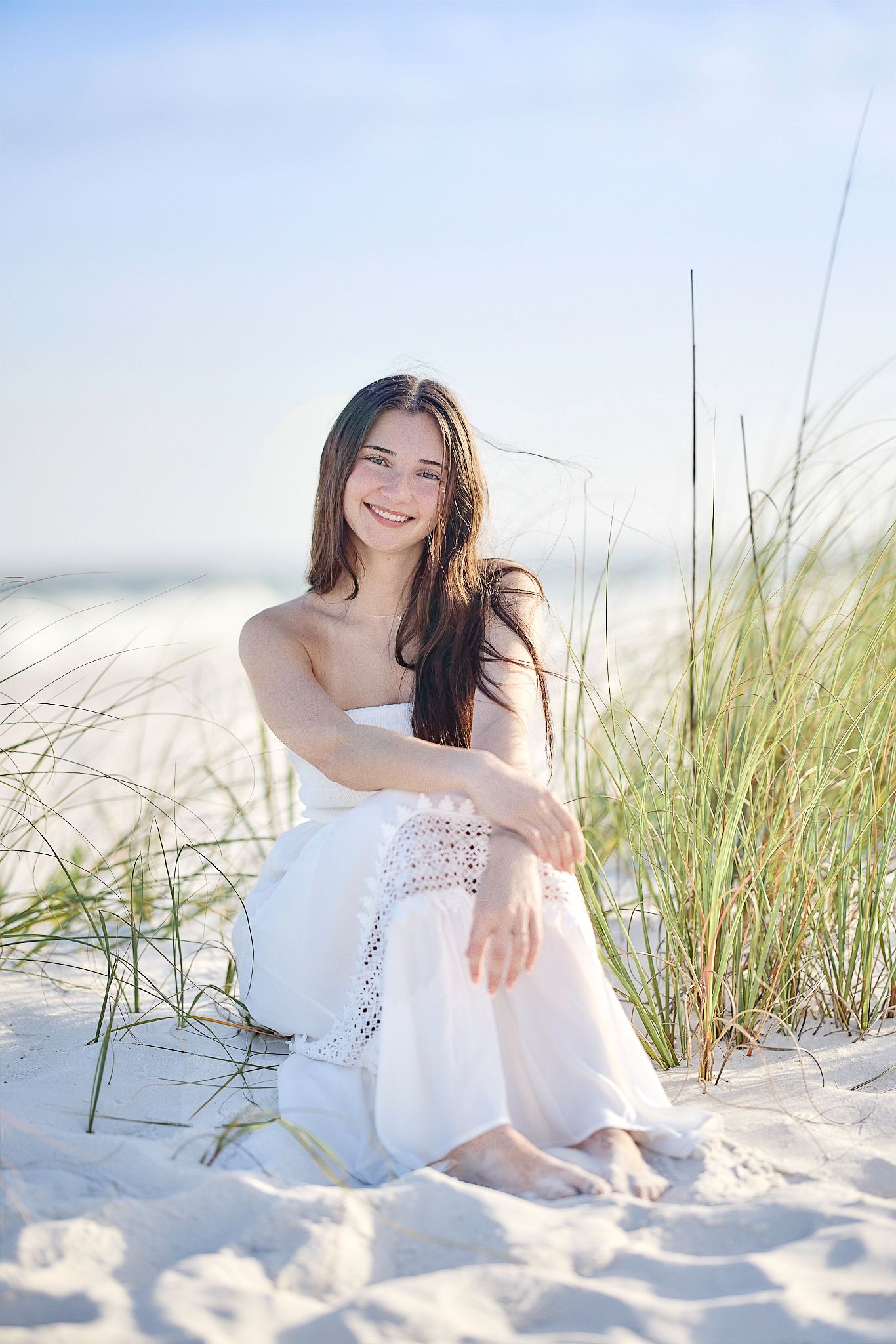A joyful summer beach photo with soft lighting, white dress, and sea grass swaying in the breeze.