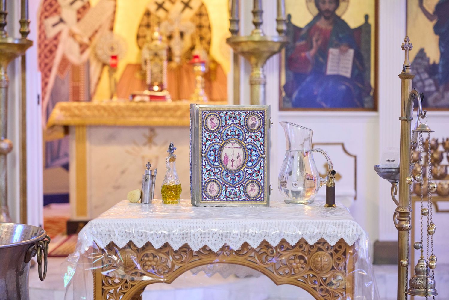 Orthodox church altar decorated with ornate gold details, white cloth, and religious icons in the background.