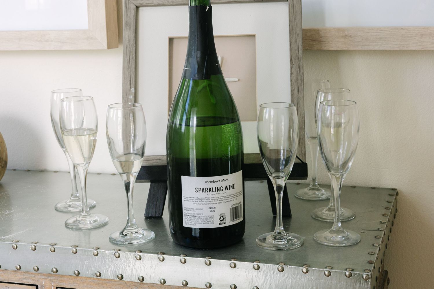 Wedding reception champagne glasses and bottles arranged on mirrored table.