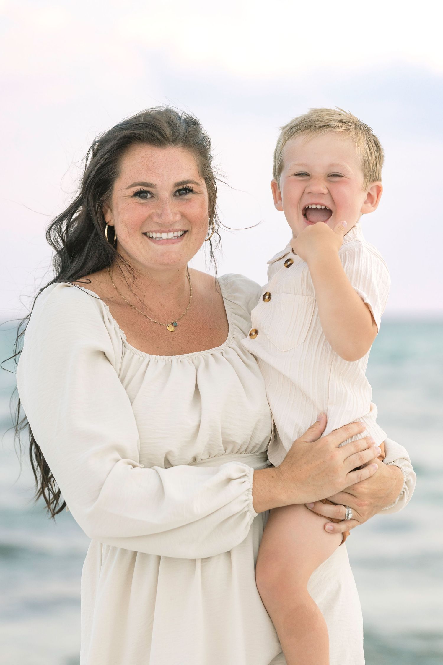 A heartwarming seaside portrait showcasing natural laughter and embraces on a bright beach day.