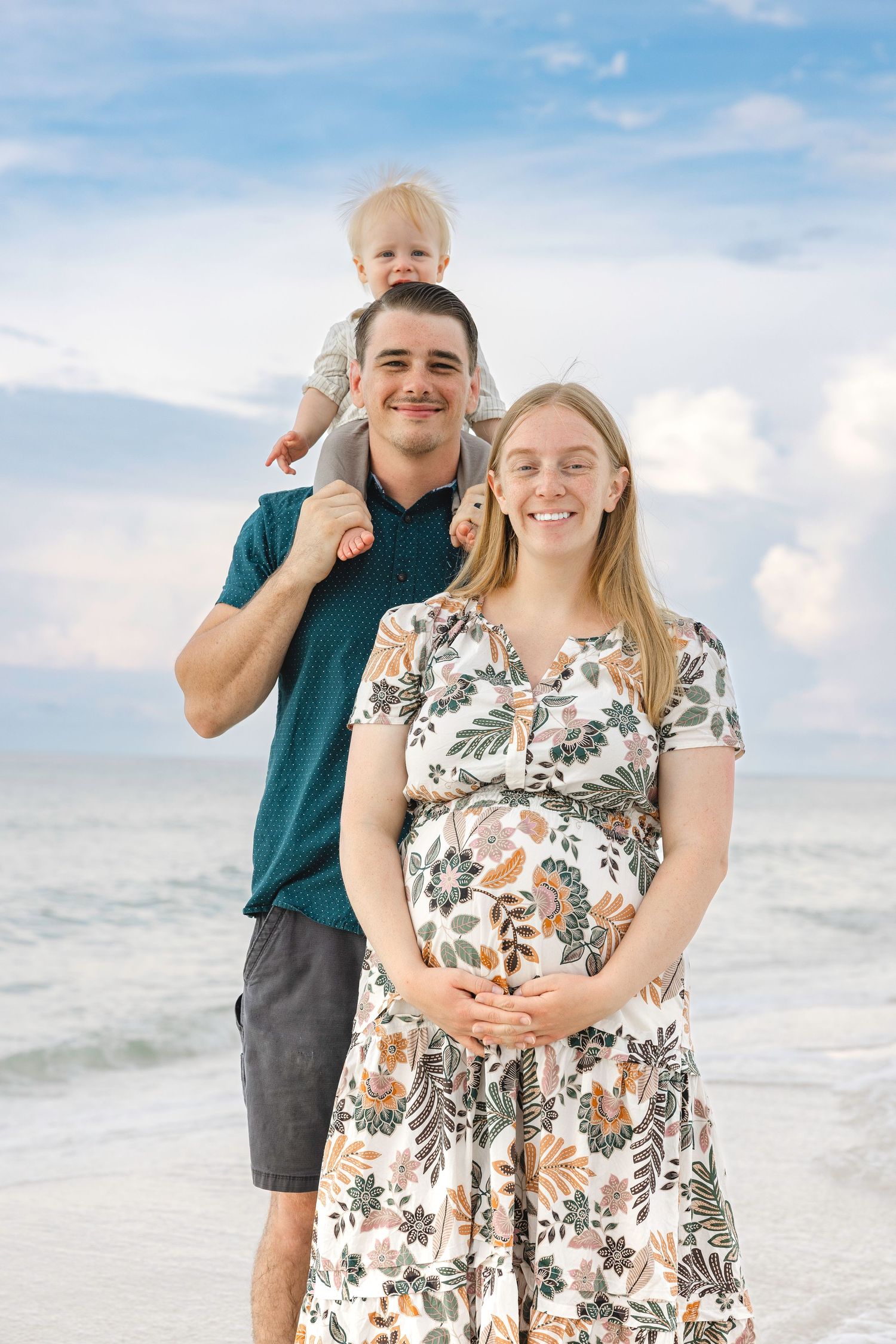 Family poses playfully together on a white sand beach during sunset with waves in background.