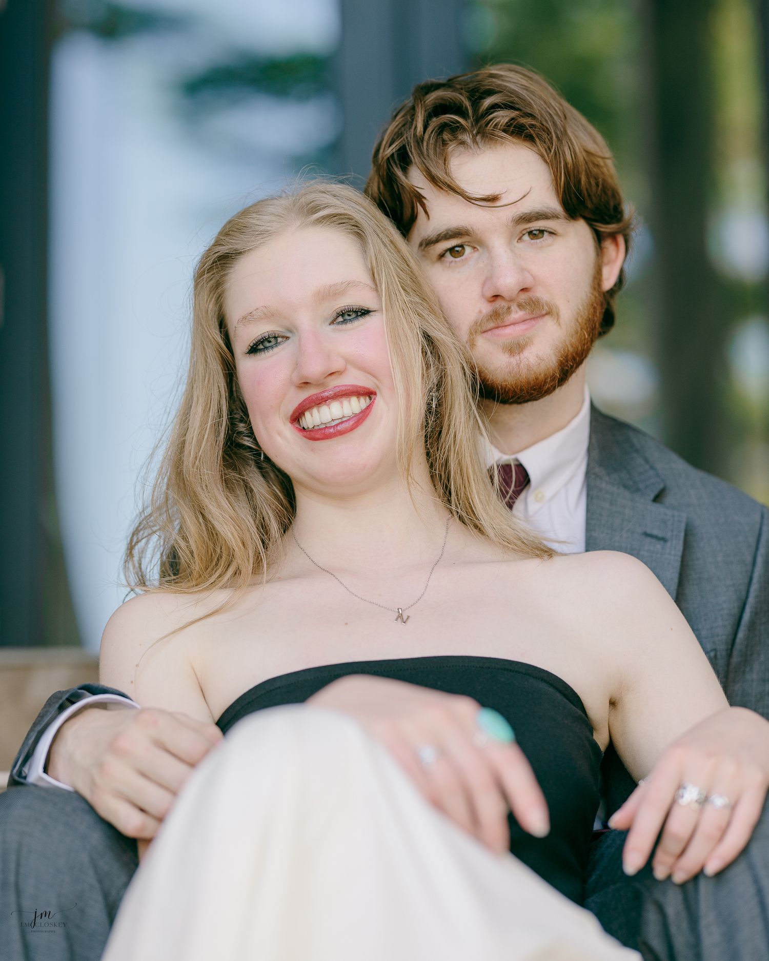 A romantic portrait of a couple in formal attire, with her in a black and white gown and him in a grey suit.