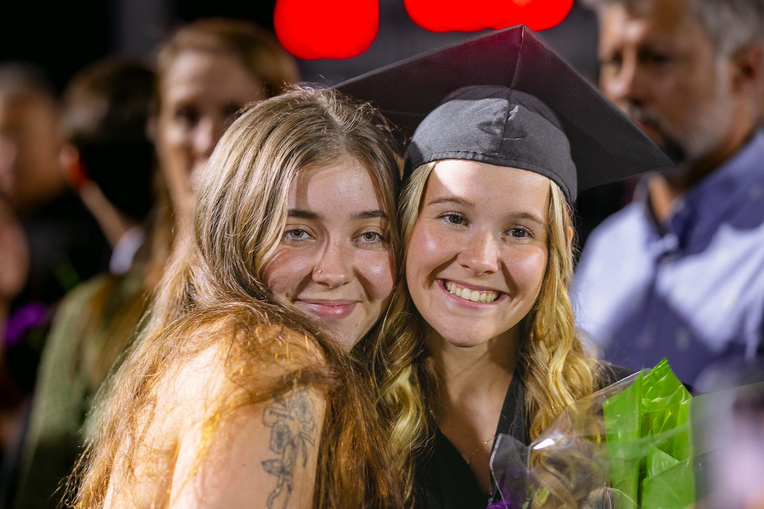 Two friends sharing a joyful moment during graduation celebrations.