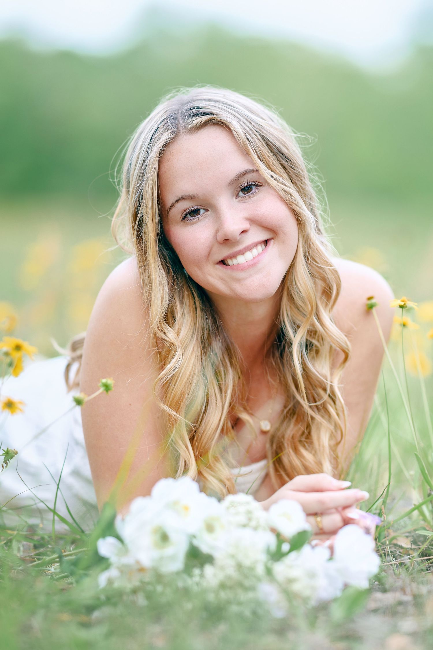 Close-up outdoor portrait amidst yellow wildflowers with white floral bouquet.