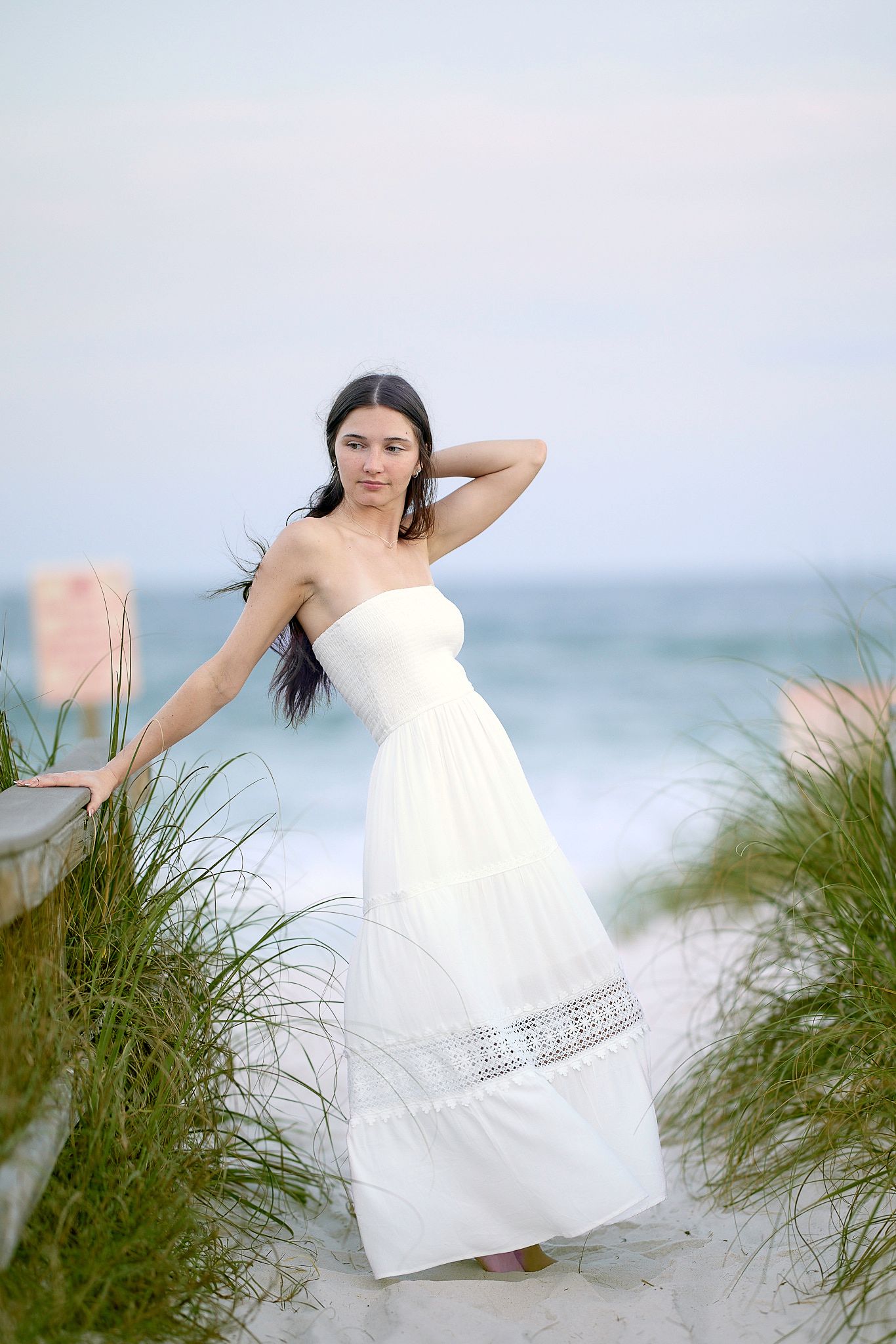 Ethereal beach photography with flowing white dress among sea oats at dusk.