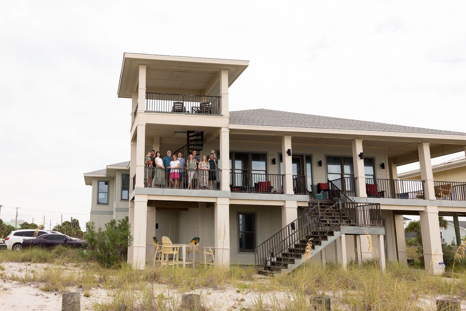 Beach house stilted buildings with stairs and decks overlooking coastal dunes and sand.