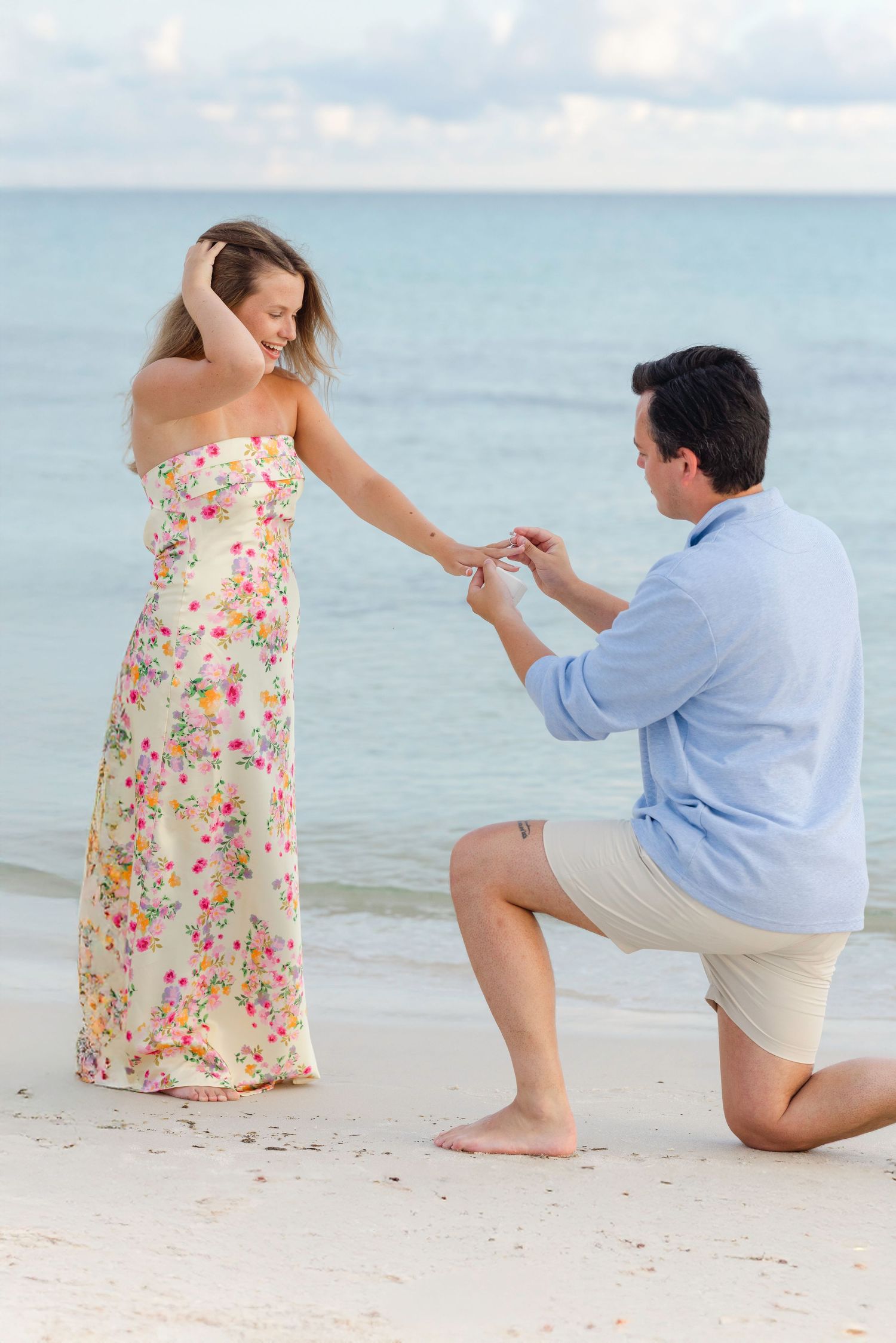 A romantic beach proposal sequence showing a couple on white sand with turquoise water in the background.