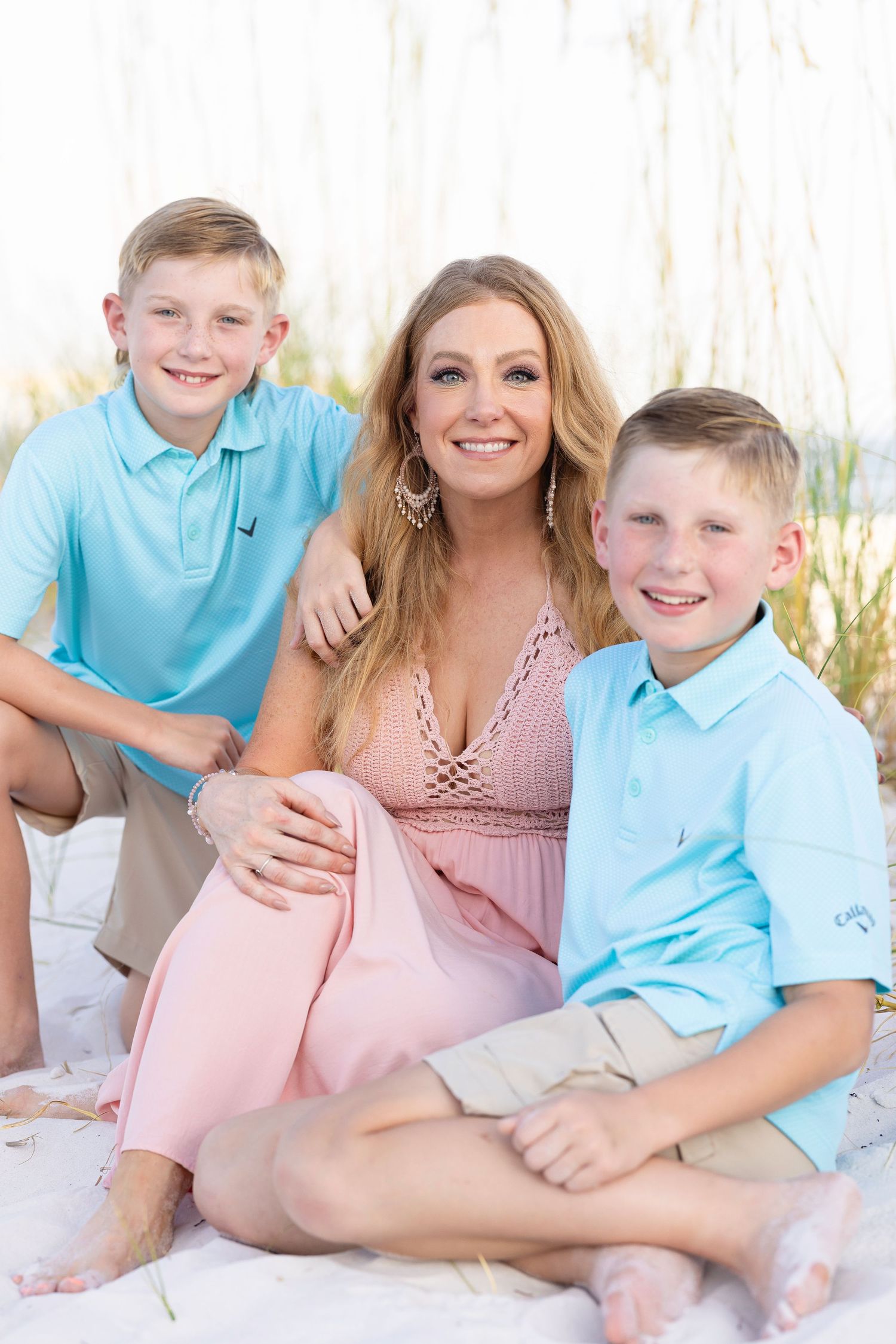 Family posing together among beach grass on a sunny day.