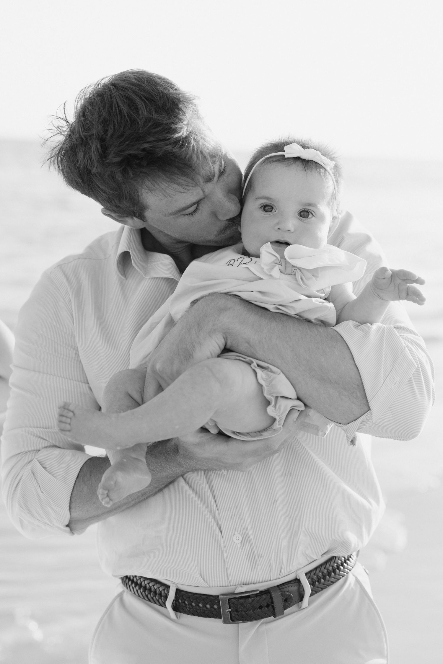 A series of tender black and white photos showing intimate moments between a parent and baby against a light background.