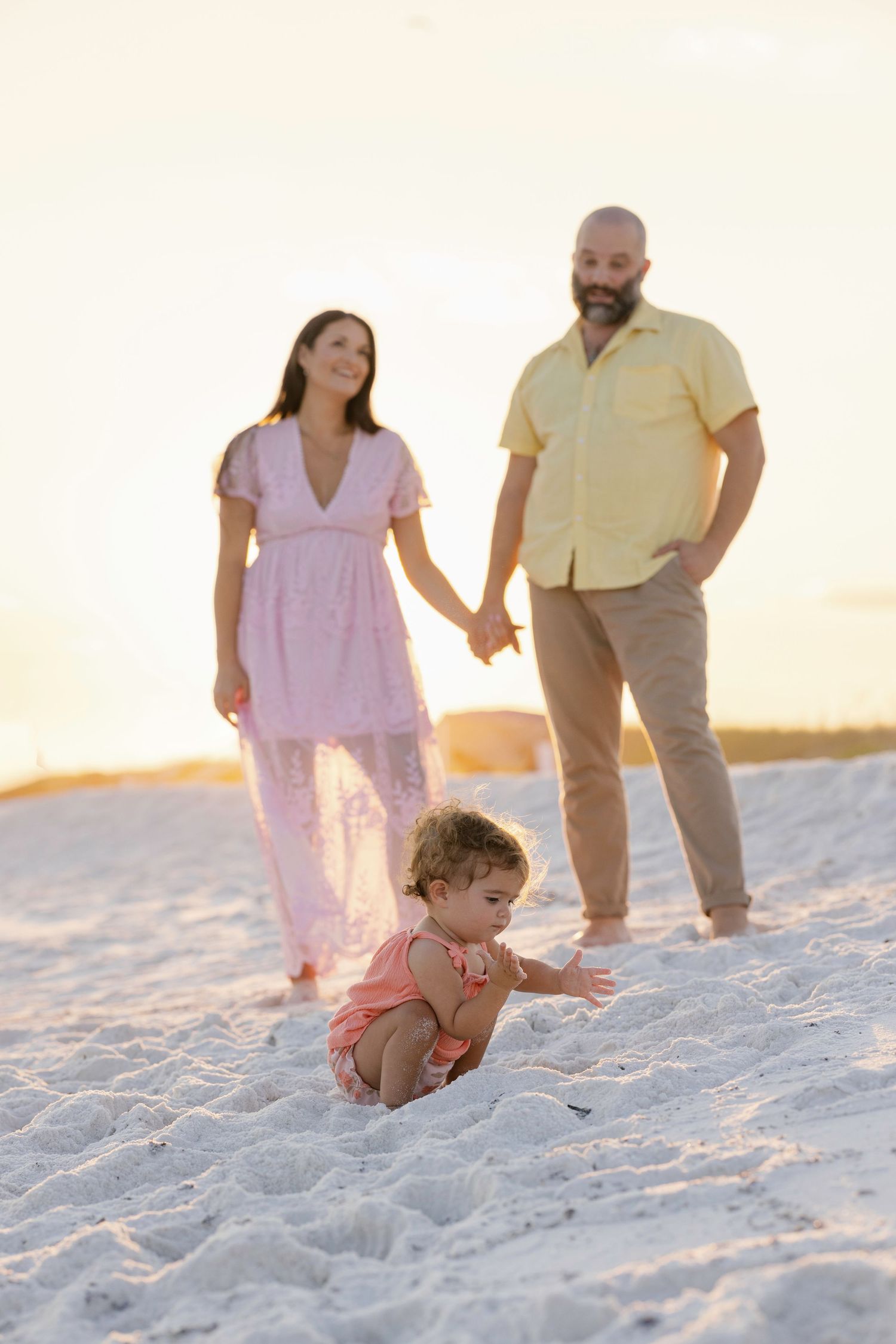 Family enjoying a peaceful moment on a pristine white sand beach during golden hour.