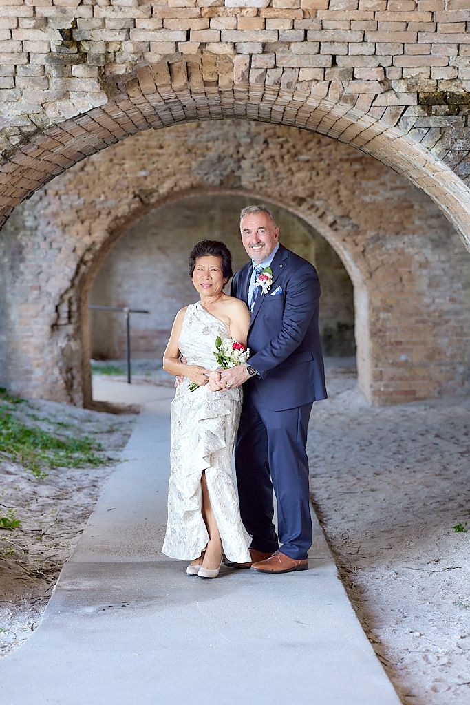 A couple poses under a historic brick archway in a series of romantic wedding photos.