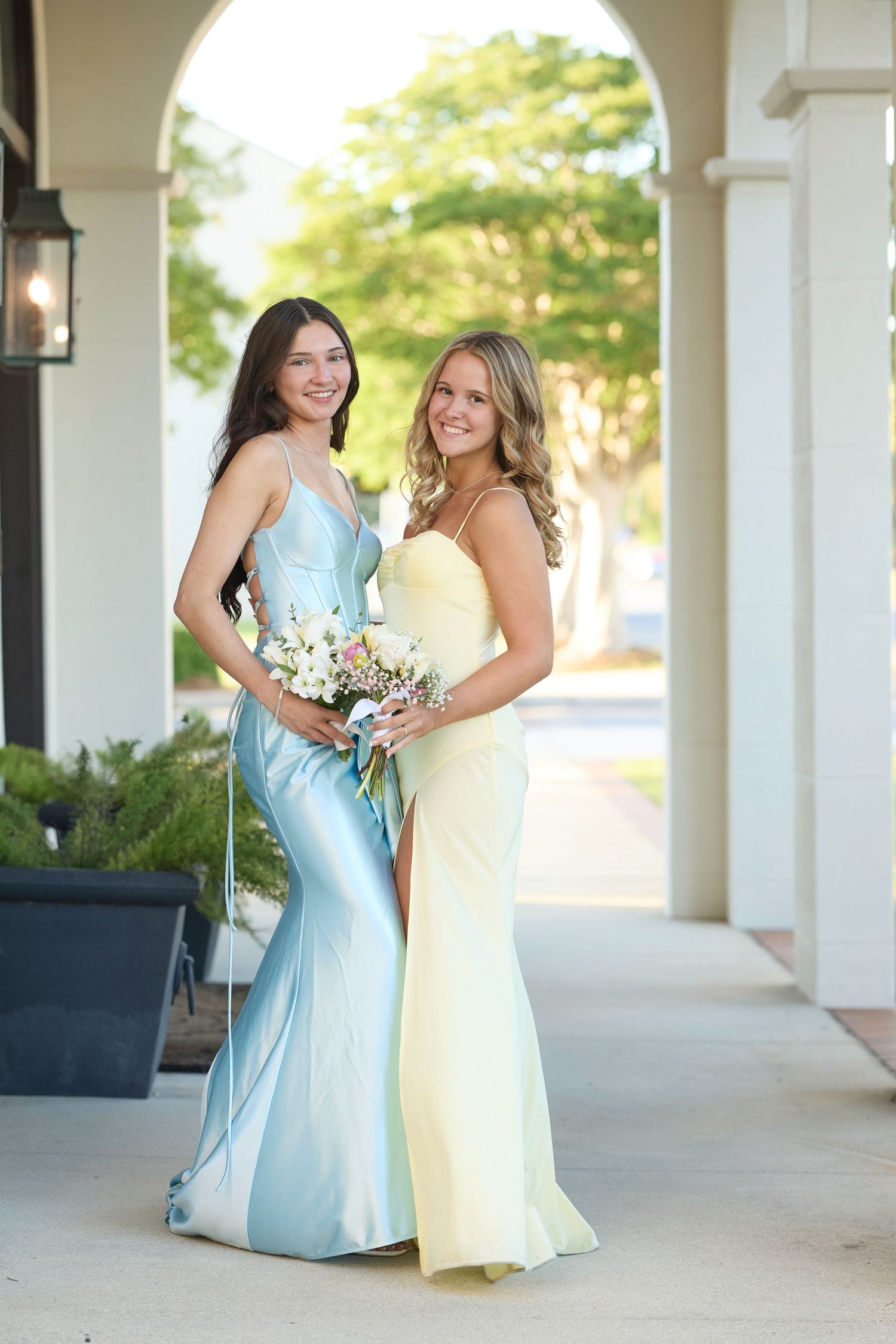 Four sequential photos of two women in formal dresses hugging and laughing together on a white-columned porch.