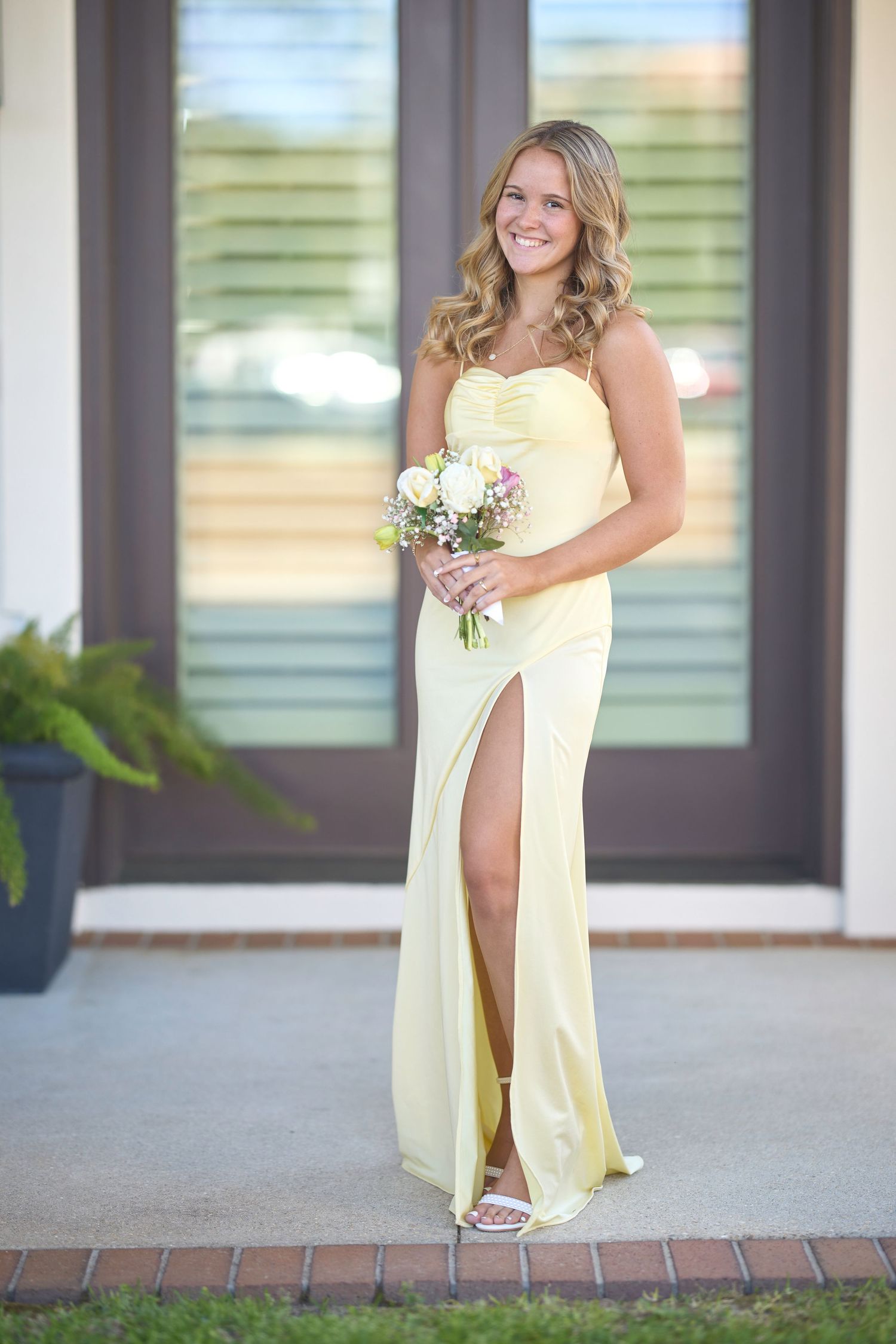 A flowing yellow dress creates graceful silhouettes against a white building exterior.