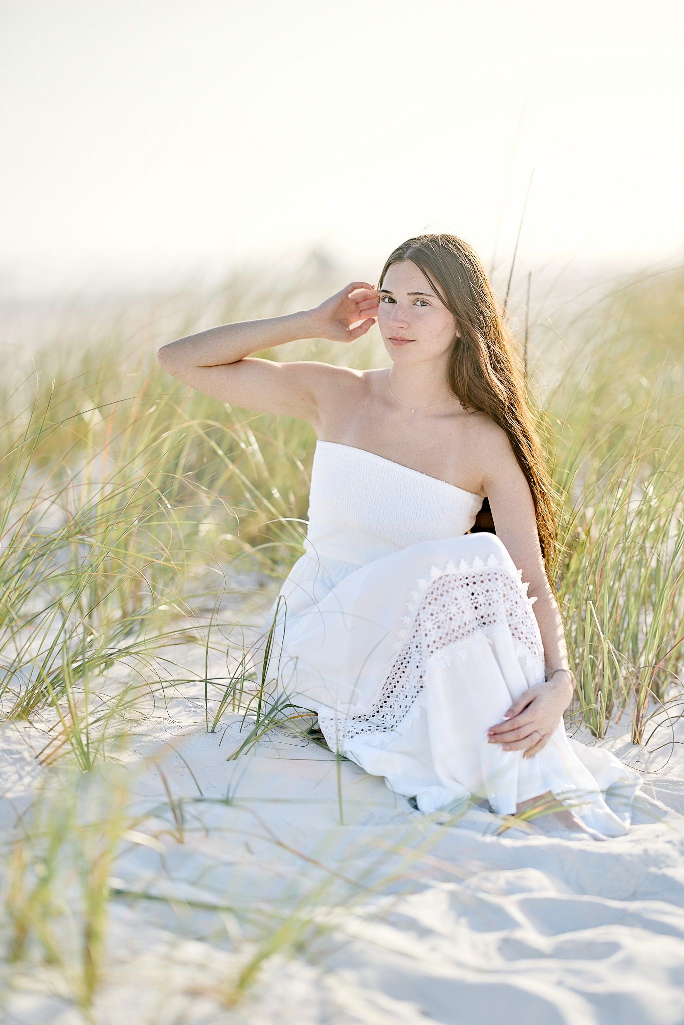 Soft natural light portrait in white dress among beach grass.
