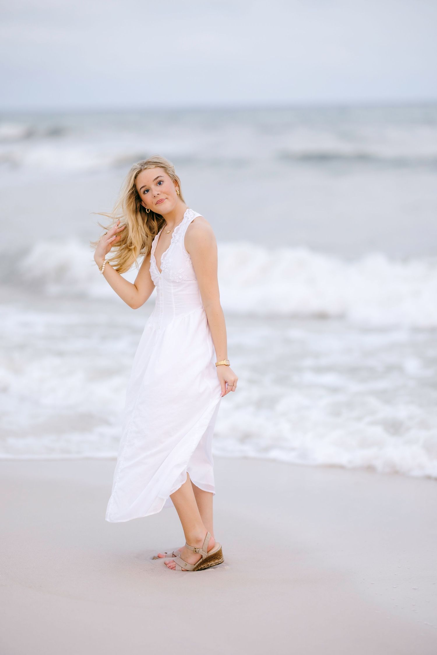 Flowing white dress catches the ocean breeze during a dreamy beach photoshoot.