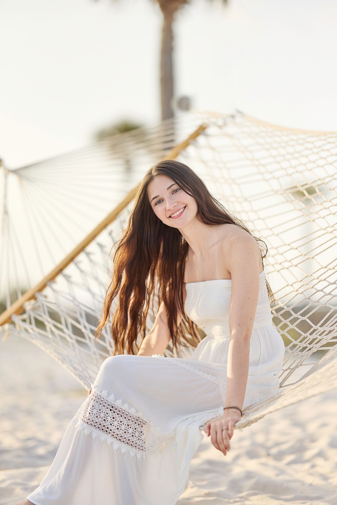 Casual beach portrait relaxing in a hammock wearing a white sundress.