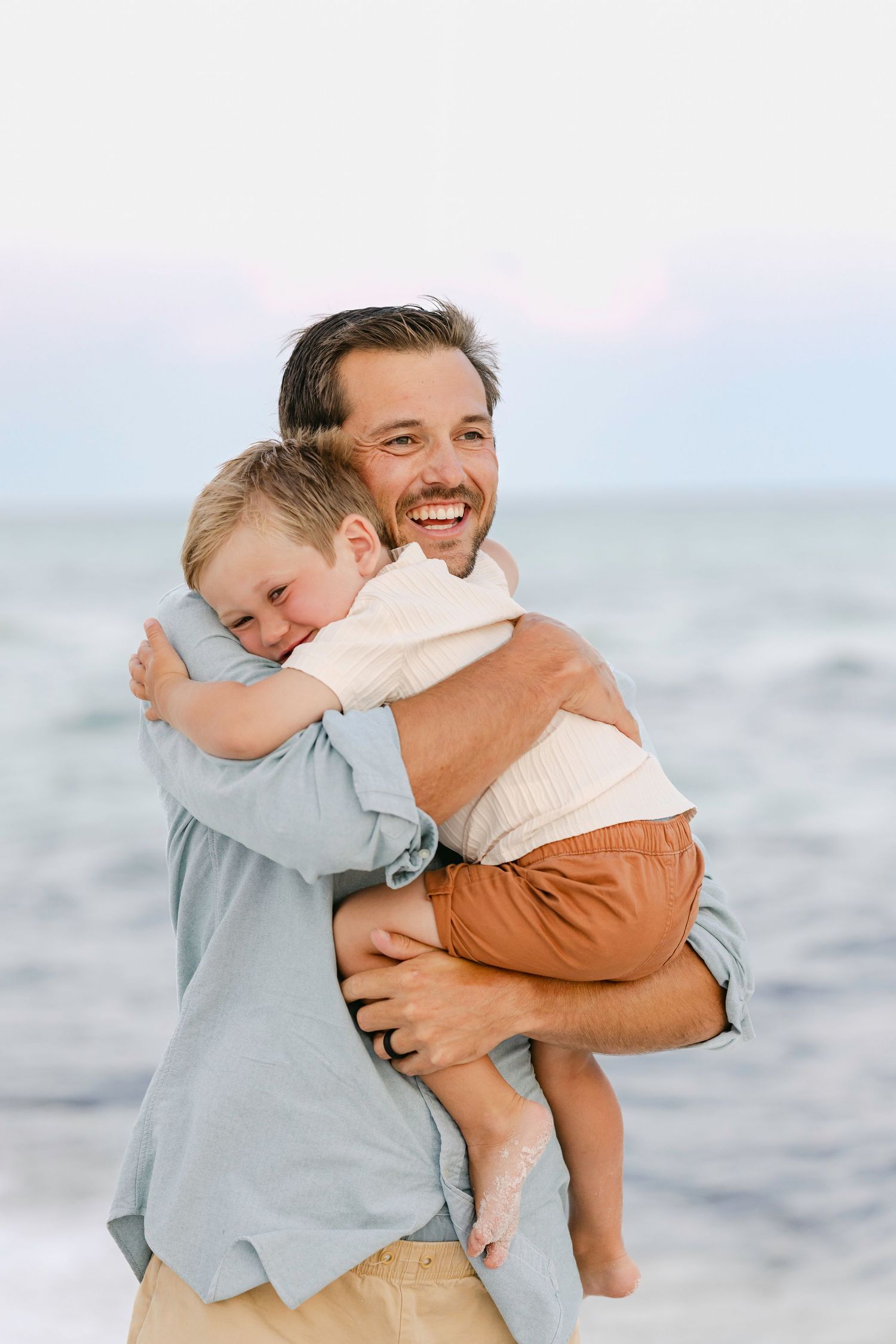 Beach photoshoot sequence showing joyful and playful interaction between two people embracing by the ocean.