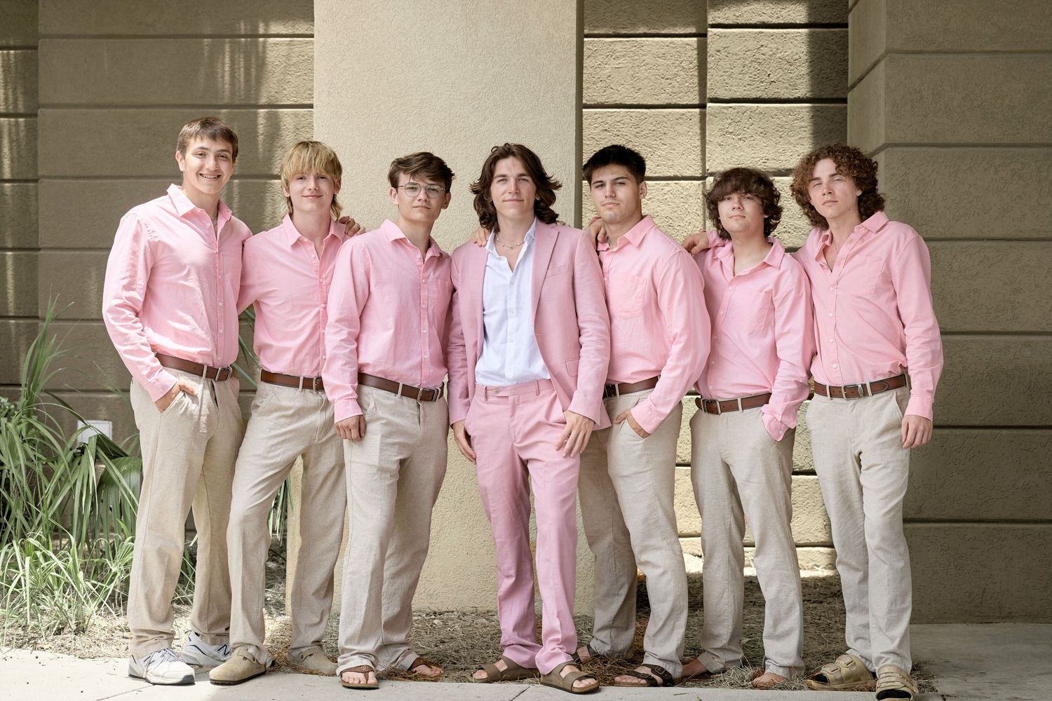 A creative collage of photos showing a group in matching pink shirts and khaki pants posing together on a porch.