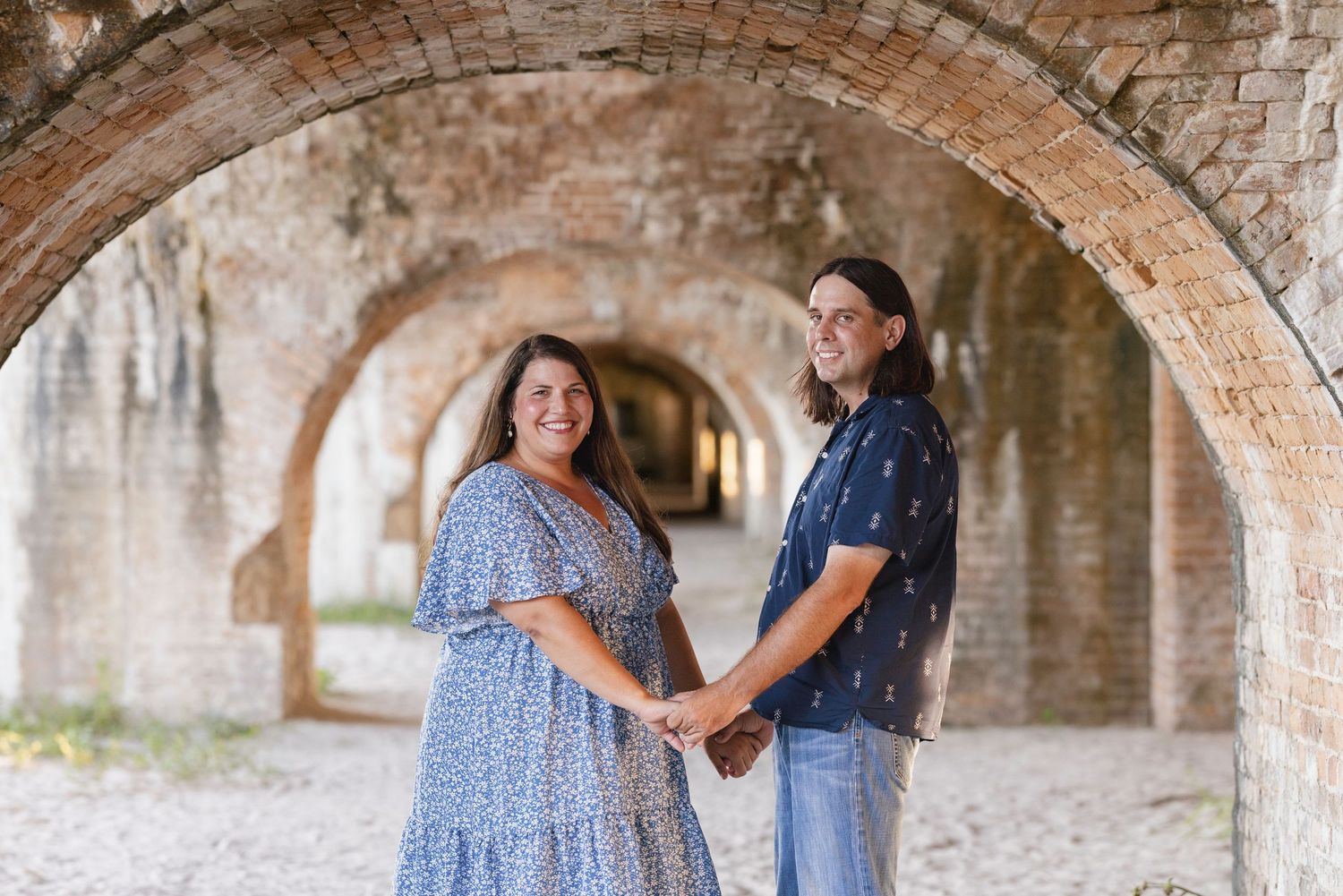 Couple holding hands and smiling under brick arches at Fort Jefferson, Dry Tortugas, Florida.